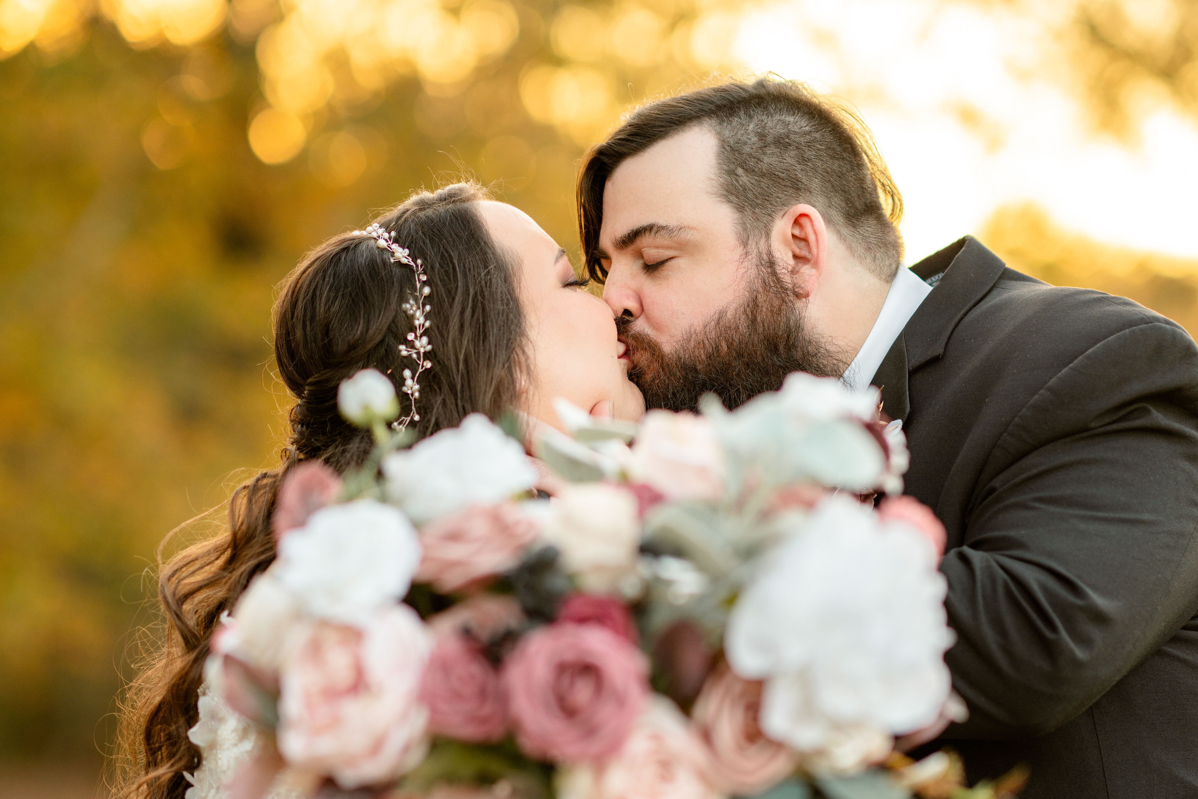 New bride and groom smootch behind bouquet