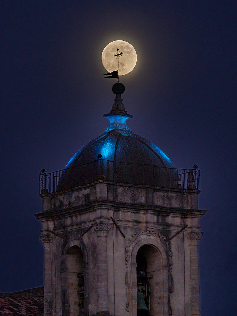 Cosenza, Italy - The yellow moon behind the bell's tower cross