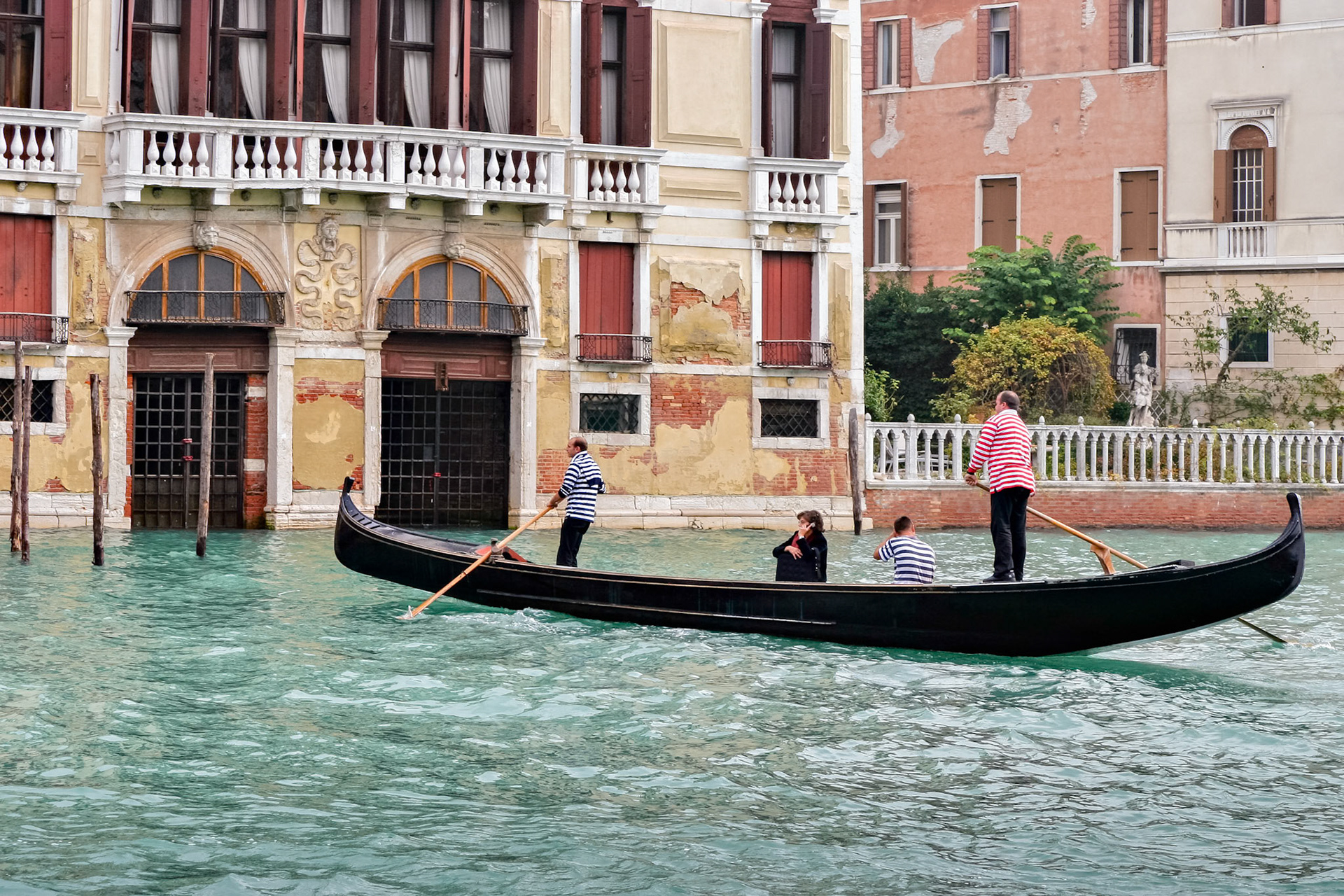 Two Gondoliers Ferrying Passengers along the Canals of Venice