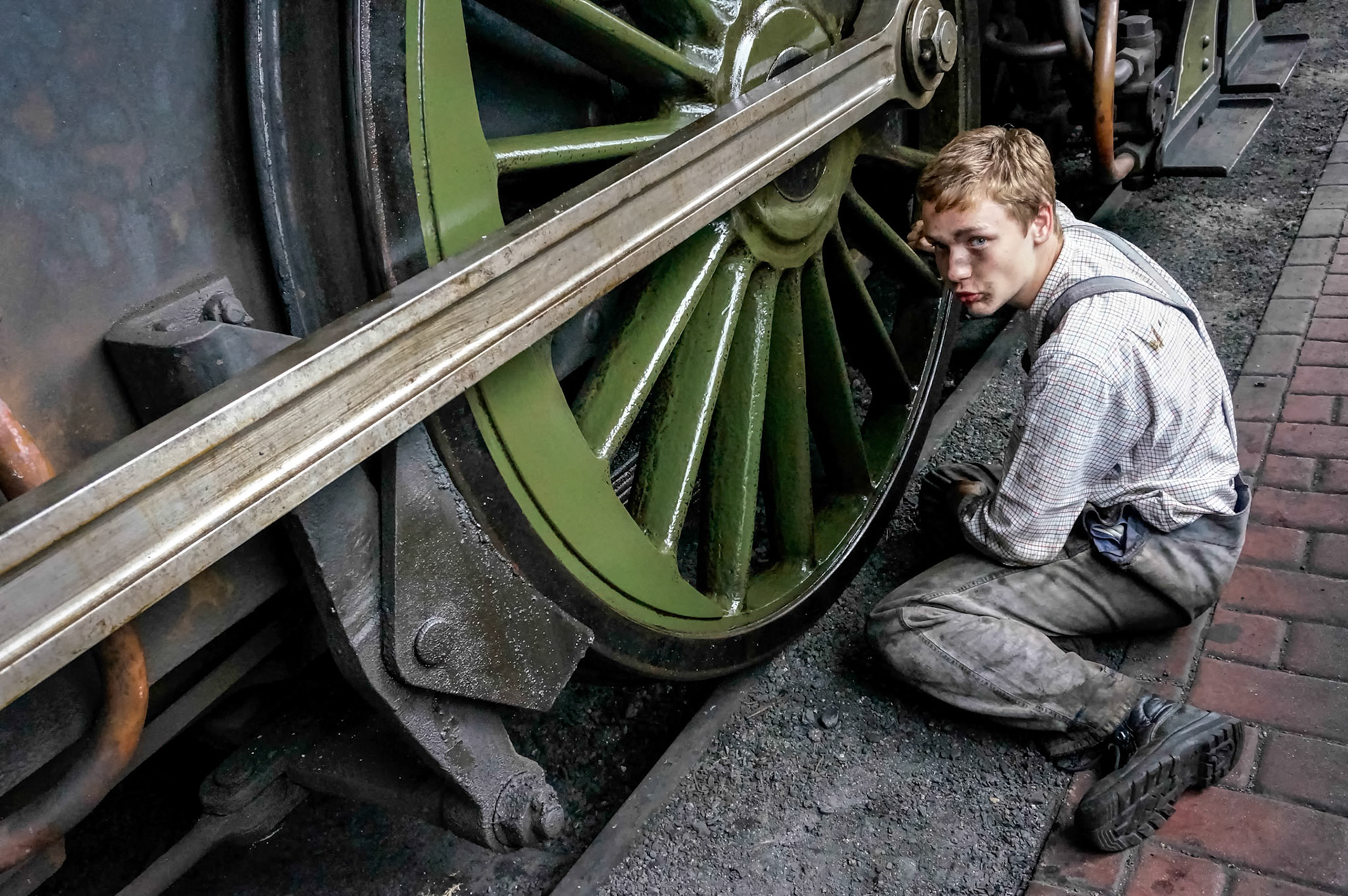 Young Man Cleaning a Steam Train Wheel