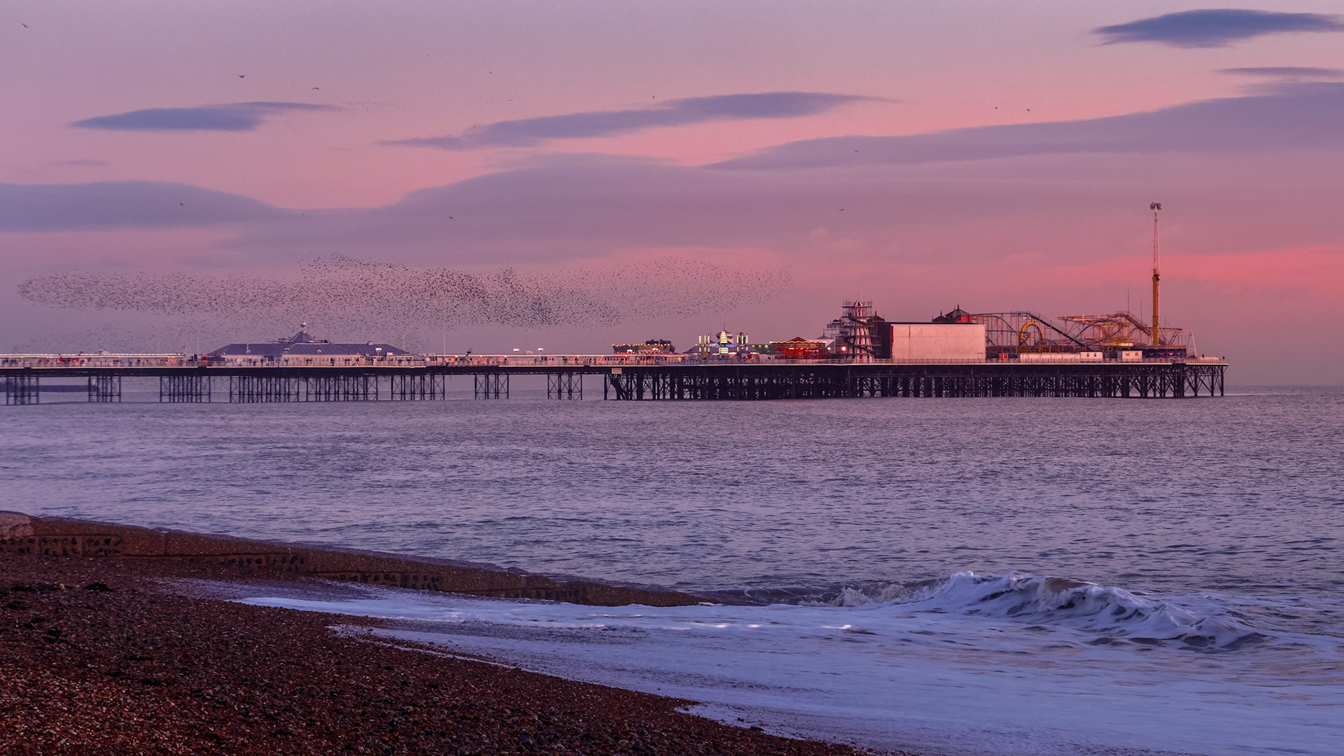 BRIGHTON, EAST SUSSEX/UK - JANUARY 26 : Starlings over the Pier in Brighton East Sussex on January 26, 2018. Unidentified people