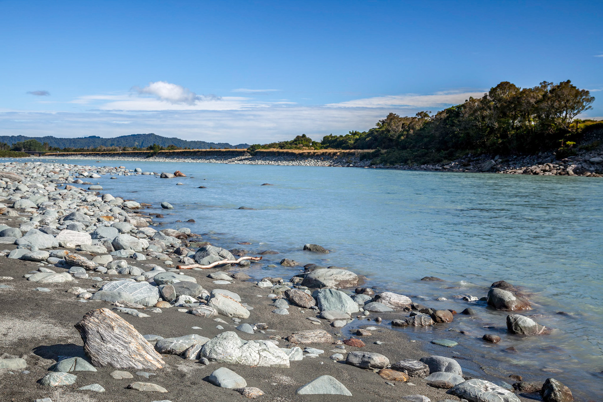 Countless rocks strewn along the Okarito River in New Zealand