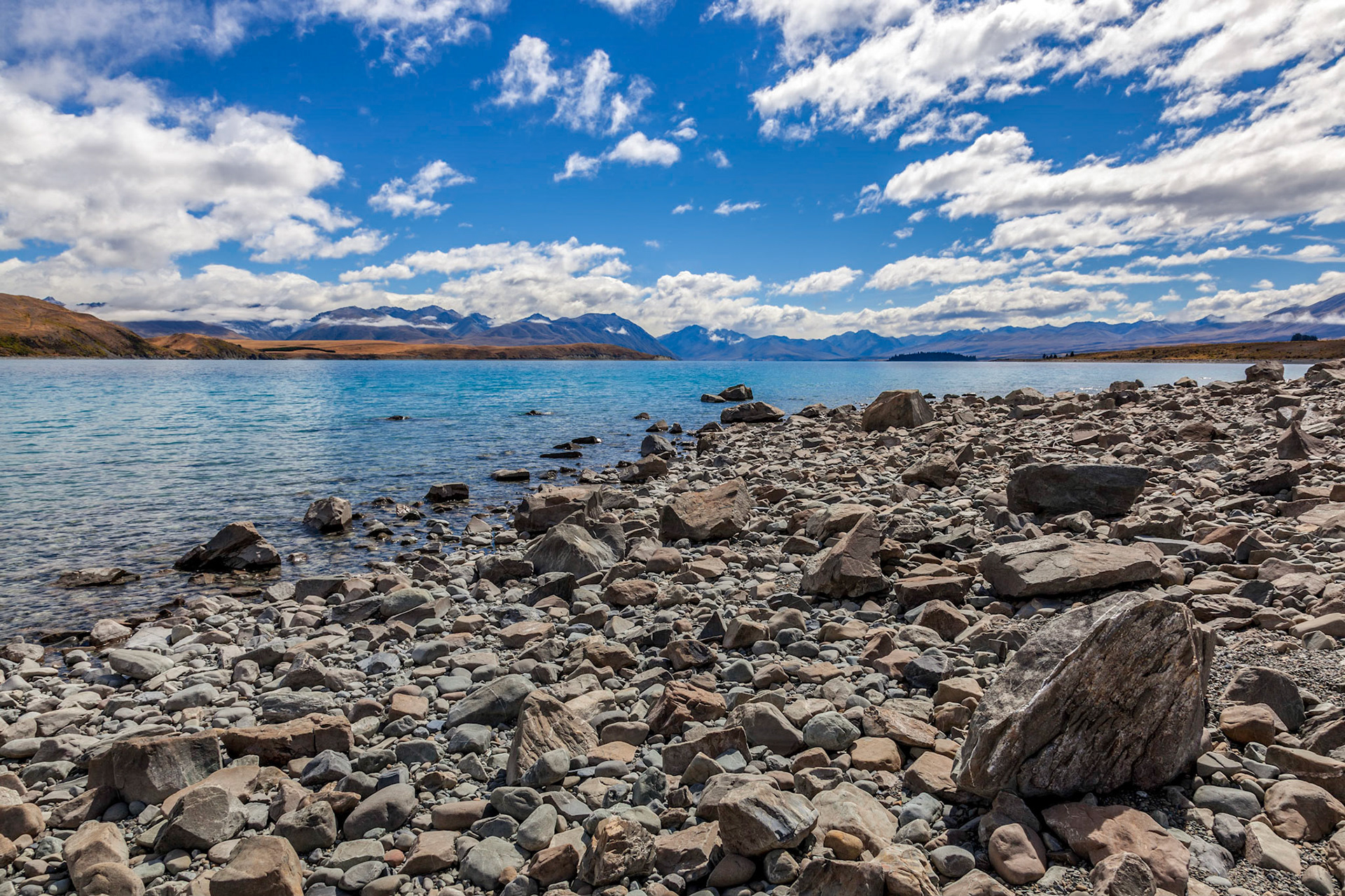 The rock strewn shoreline of Lake Tekapo in the South Island of New Zealand