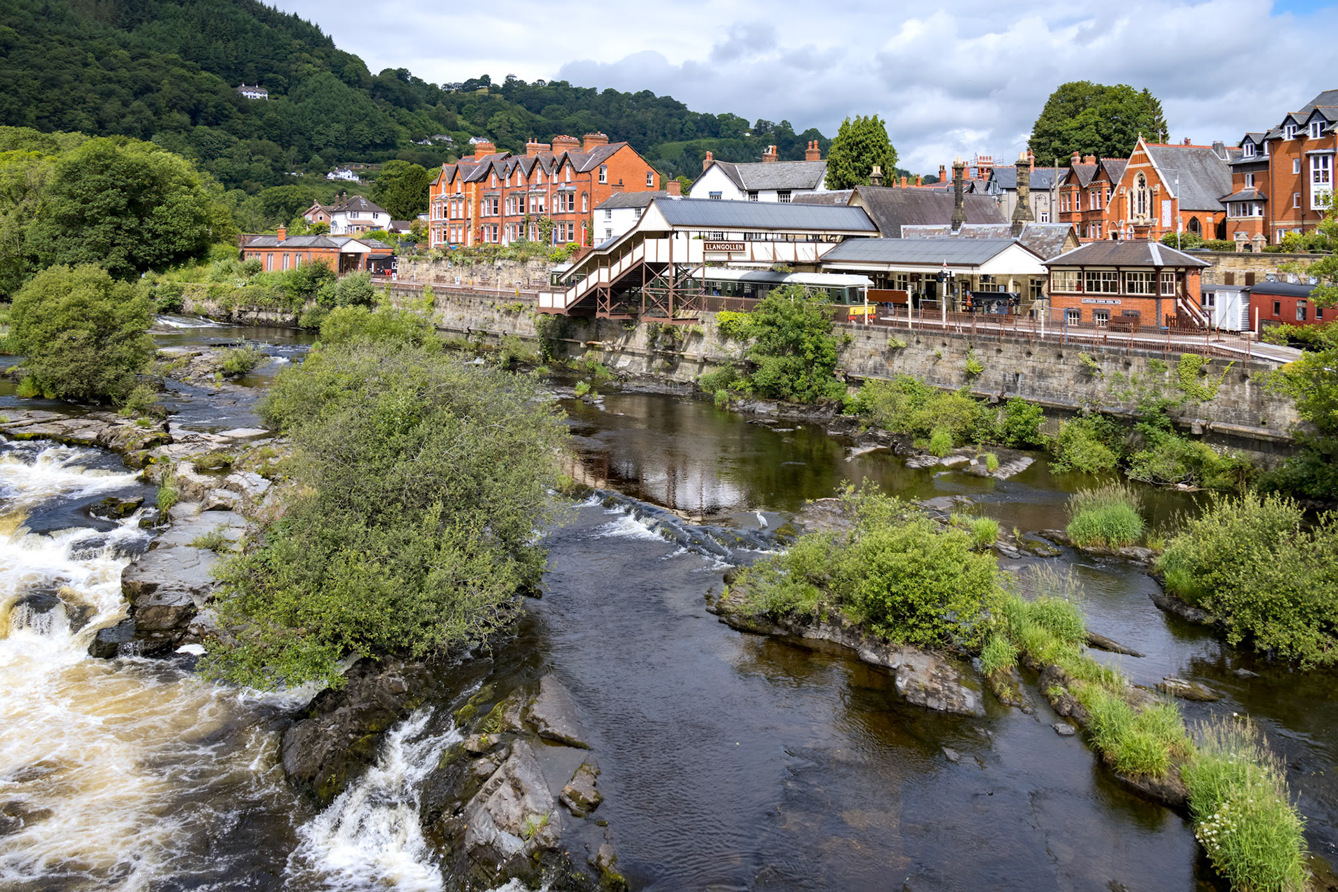 LLANGOLLEN, DENBIGHSHIRE, WALES - JULY 11 : View across the River Dee to the old station in LLangollen, Wales on July 11, 2021