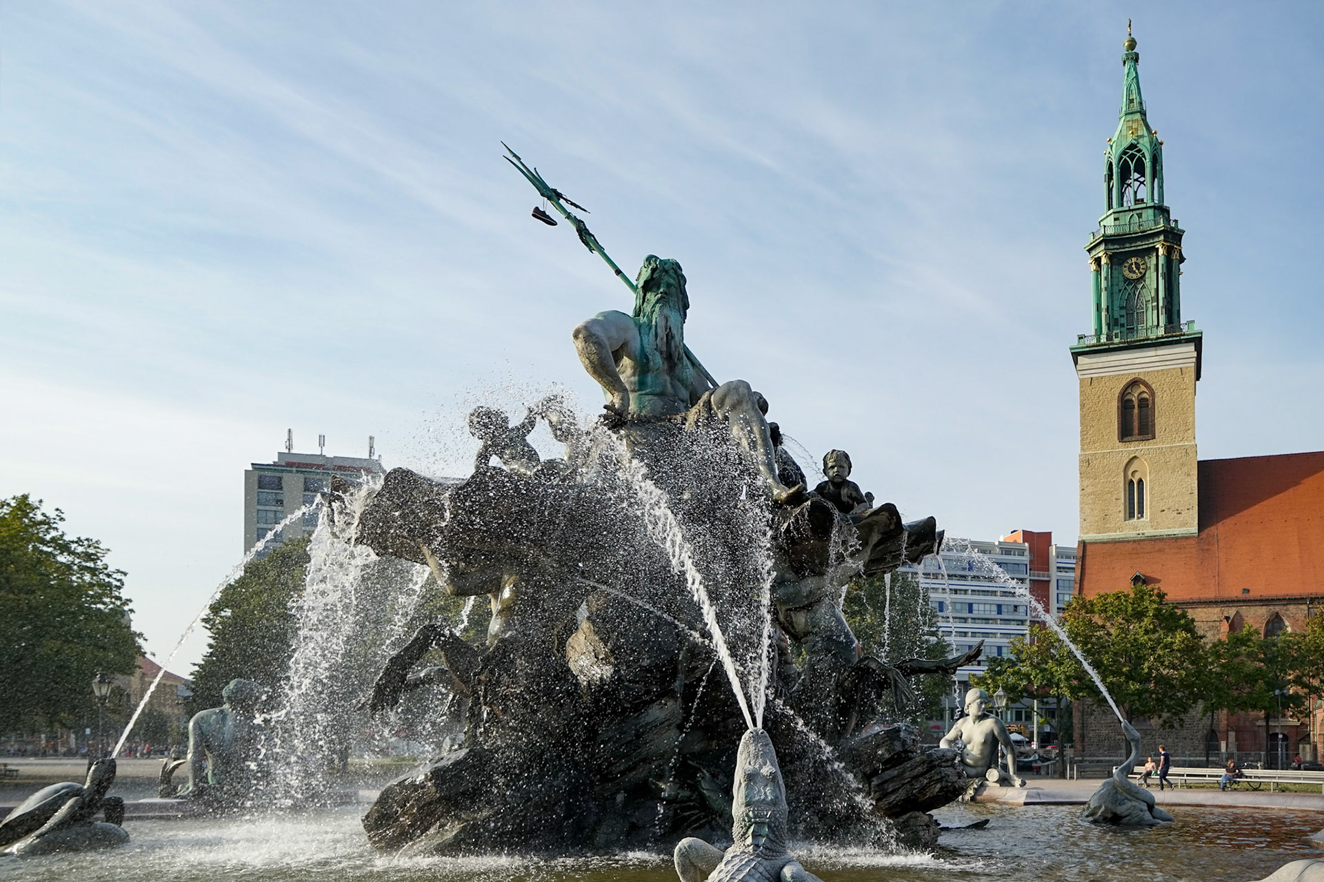 Berlin, Germany - September 15, 2014 : View of the Neptune Fountain with Marienkirche in the background in Berlin on September 15, 2014. Three unidentified people