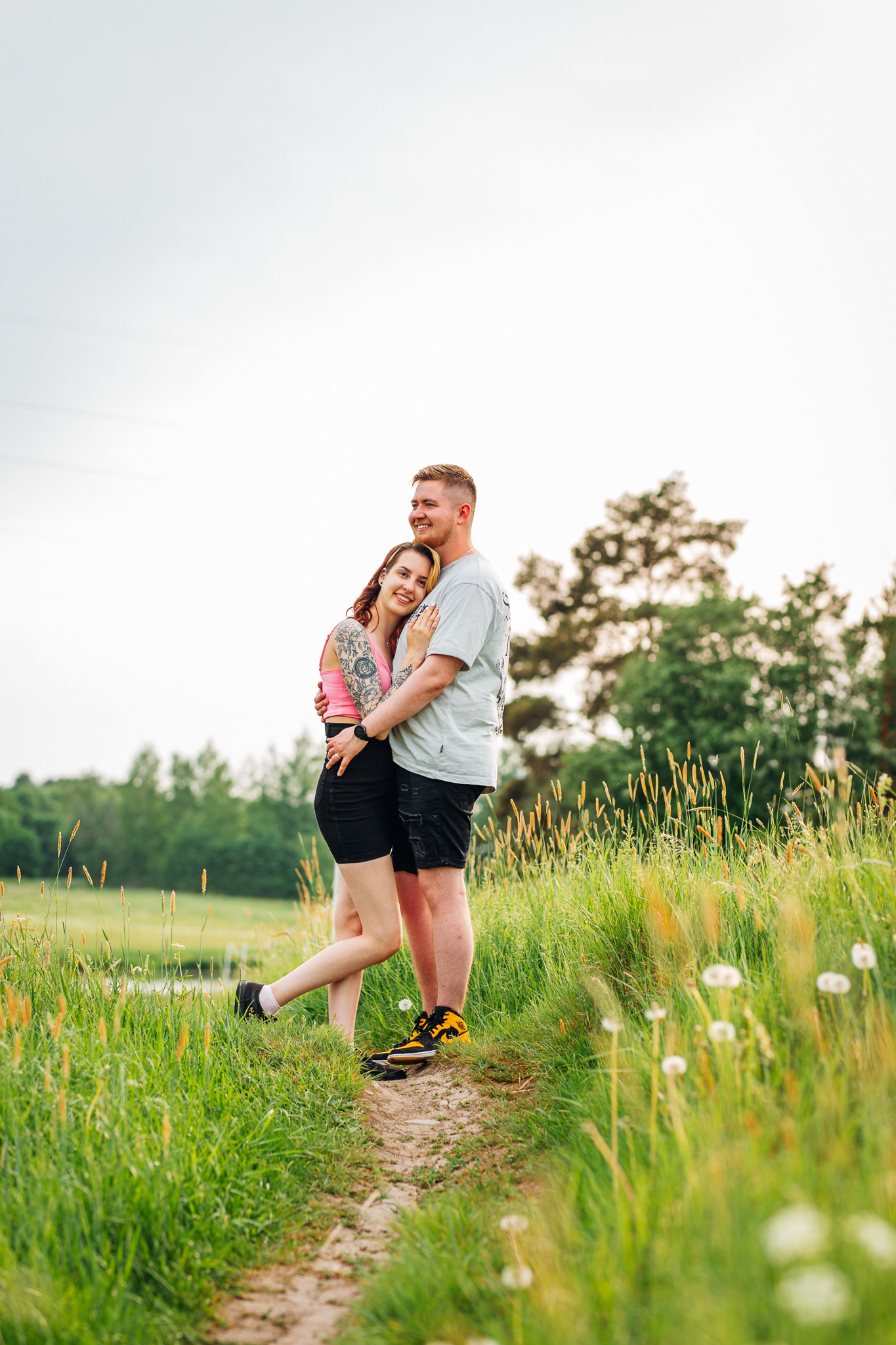 Pariskuntakuva Turussa jokivarrella heinäpellolla, jossa pari halaa ja hymyilee.