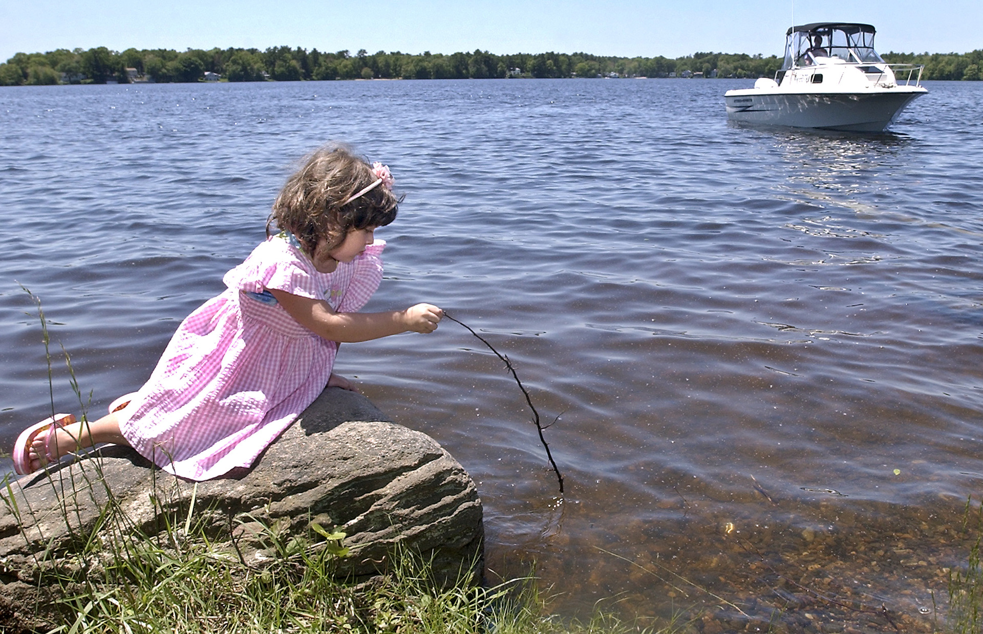 Giana Vittoriso sits on a rock at the edge of West Monponsett Pond in Halifax as her father Robert prepares the boat for a nice day out on the water.