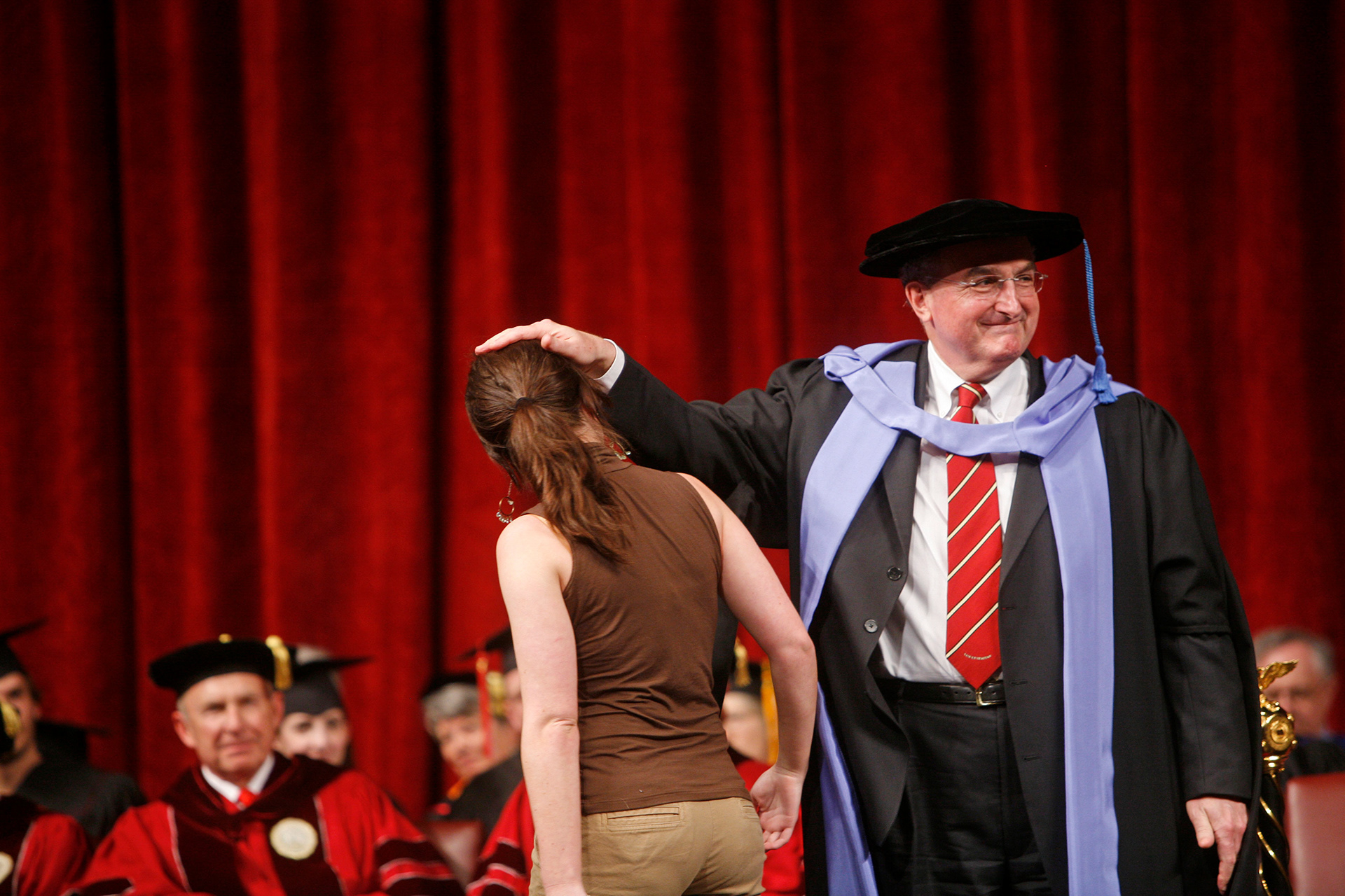 IU interim provost and future university president Michael McRobbie roughs up the hair of his daughter as she is recognized at an honors convocation.