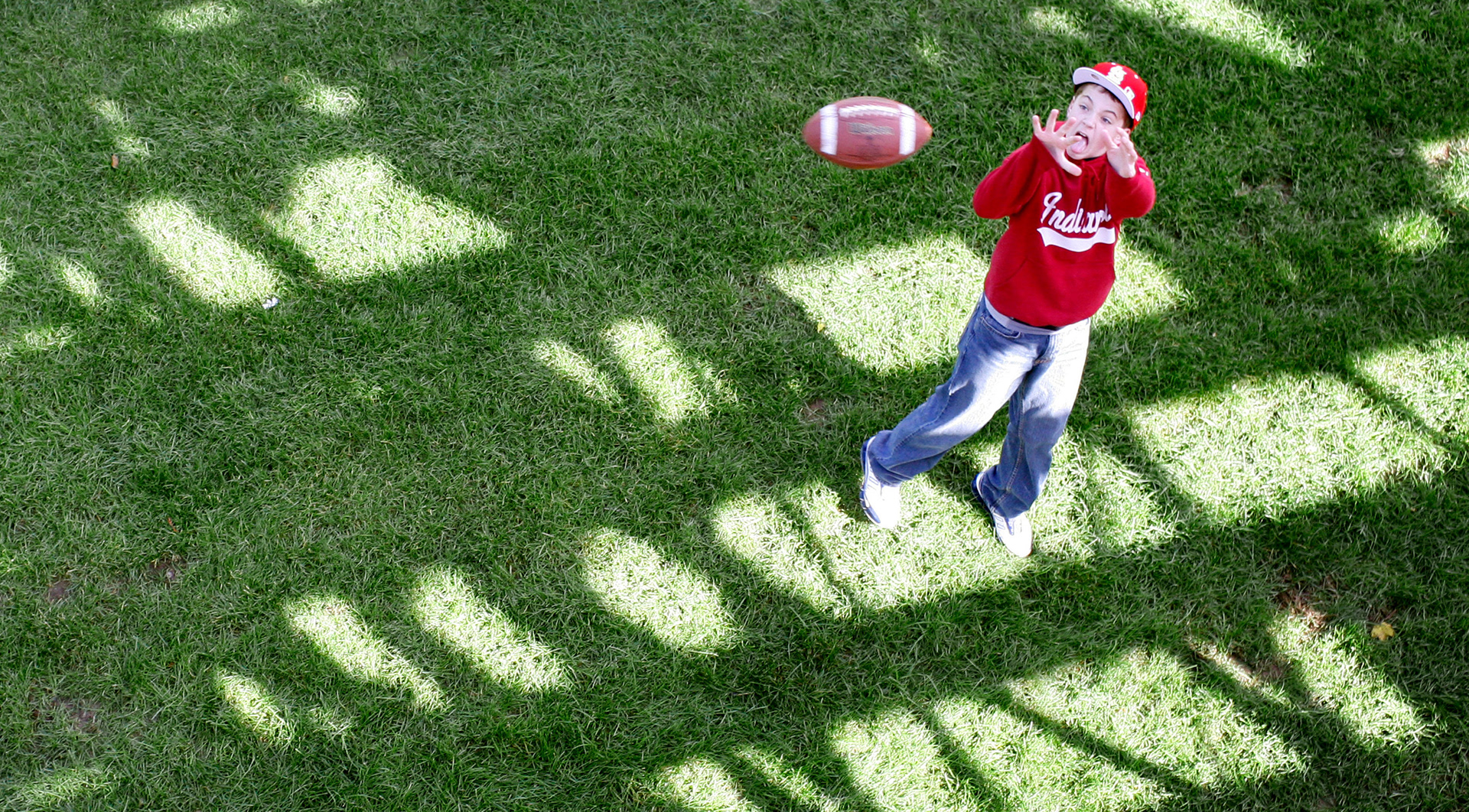 Football fans play in the shade of the stands at Memorial Stadium before a homecoming game.