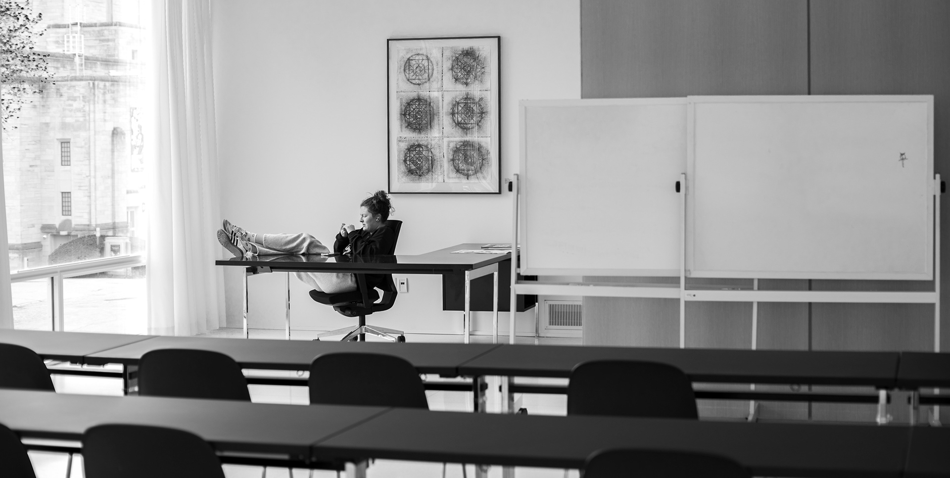 A student relaxes in an empty classroom during final exam week.