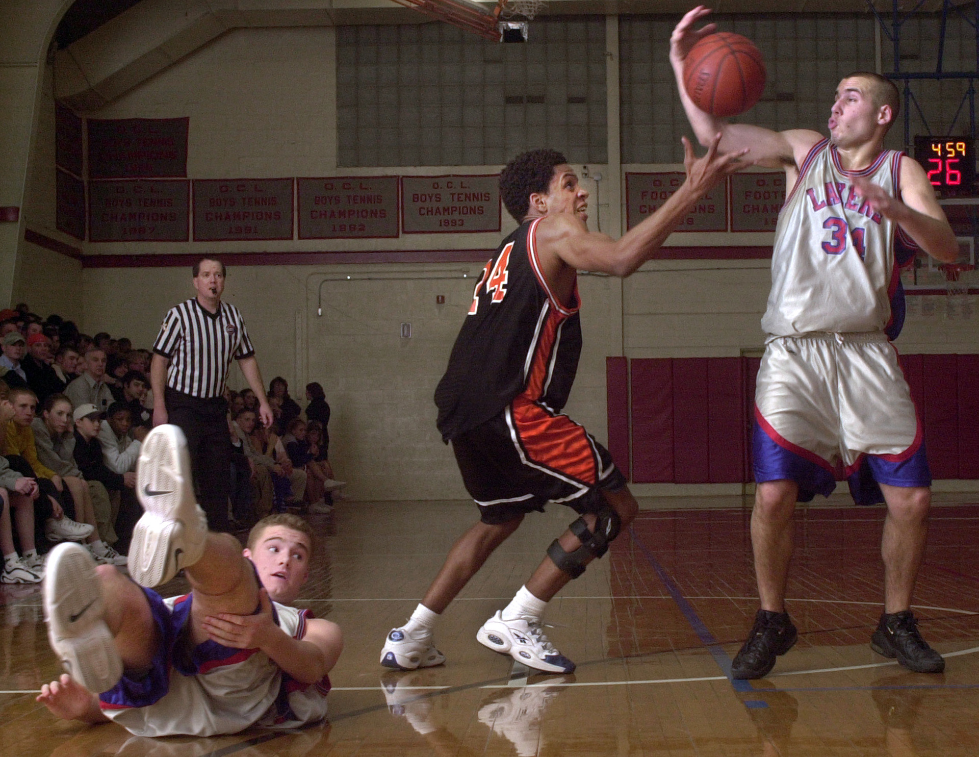 Silver Lake basketball player Chris Gregory, from left, struggles to get up off the court as Justin Lima of Taunton and Ryan Dacey battle for the ball.