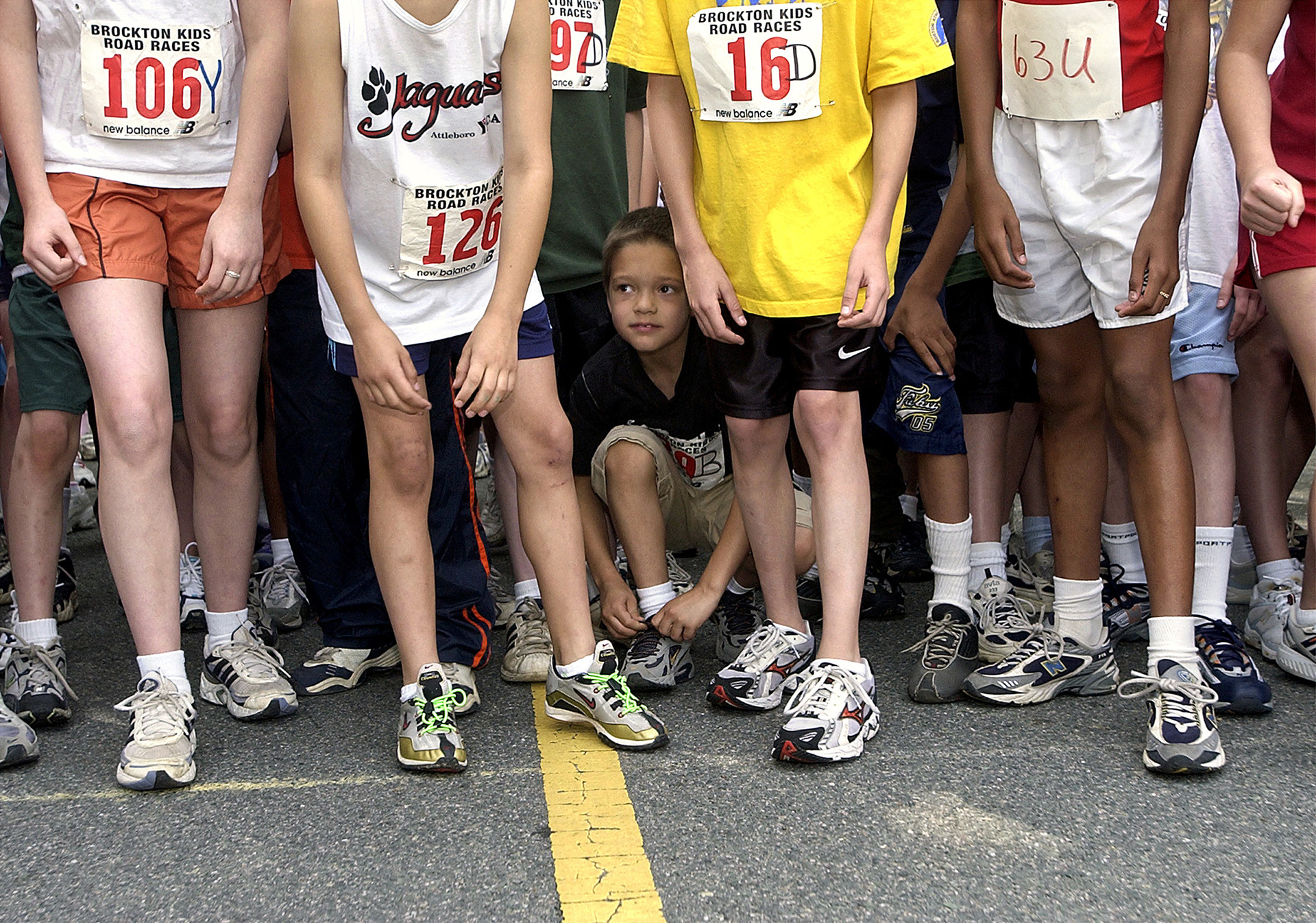 Jonathan Ortiz ties his shoes at the start line of the Kids Road Races event at D.W. Field Park in Brockton, MA.