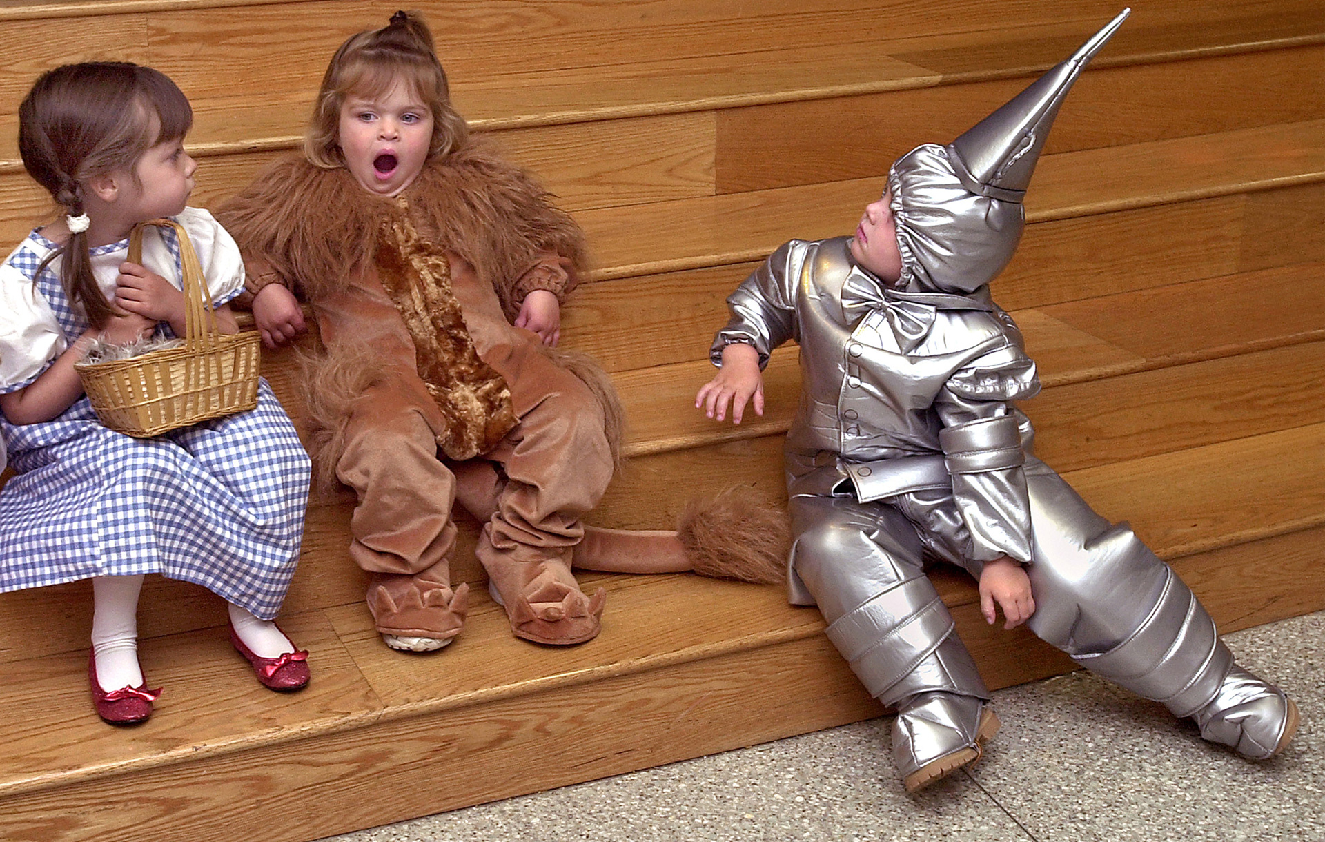 Ali Gallo, left, as Wizard of Oz character Dorothy and Nicholas Calvani, right, as the Tin Man look toward Cowardly Lion Molly Page, center, as she lets out a mighty yawn as they gather together for a costume party on Halloween.