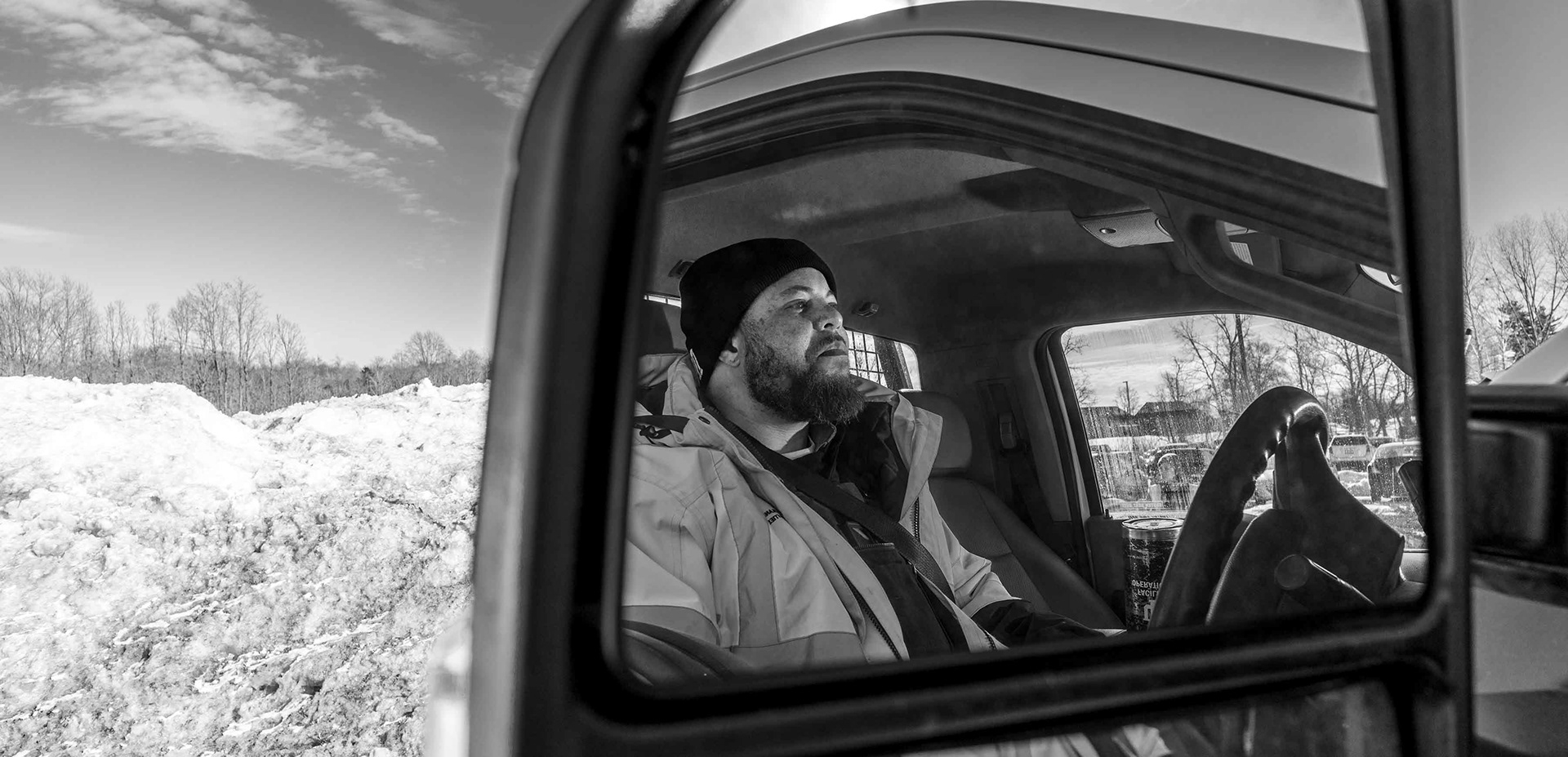 Snow removal staff member reflected in a truck's side mirror.