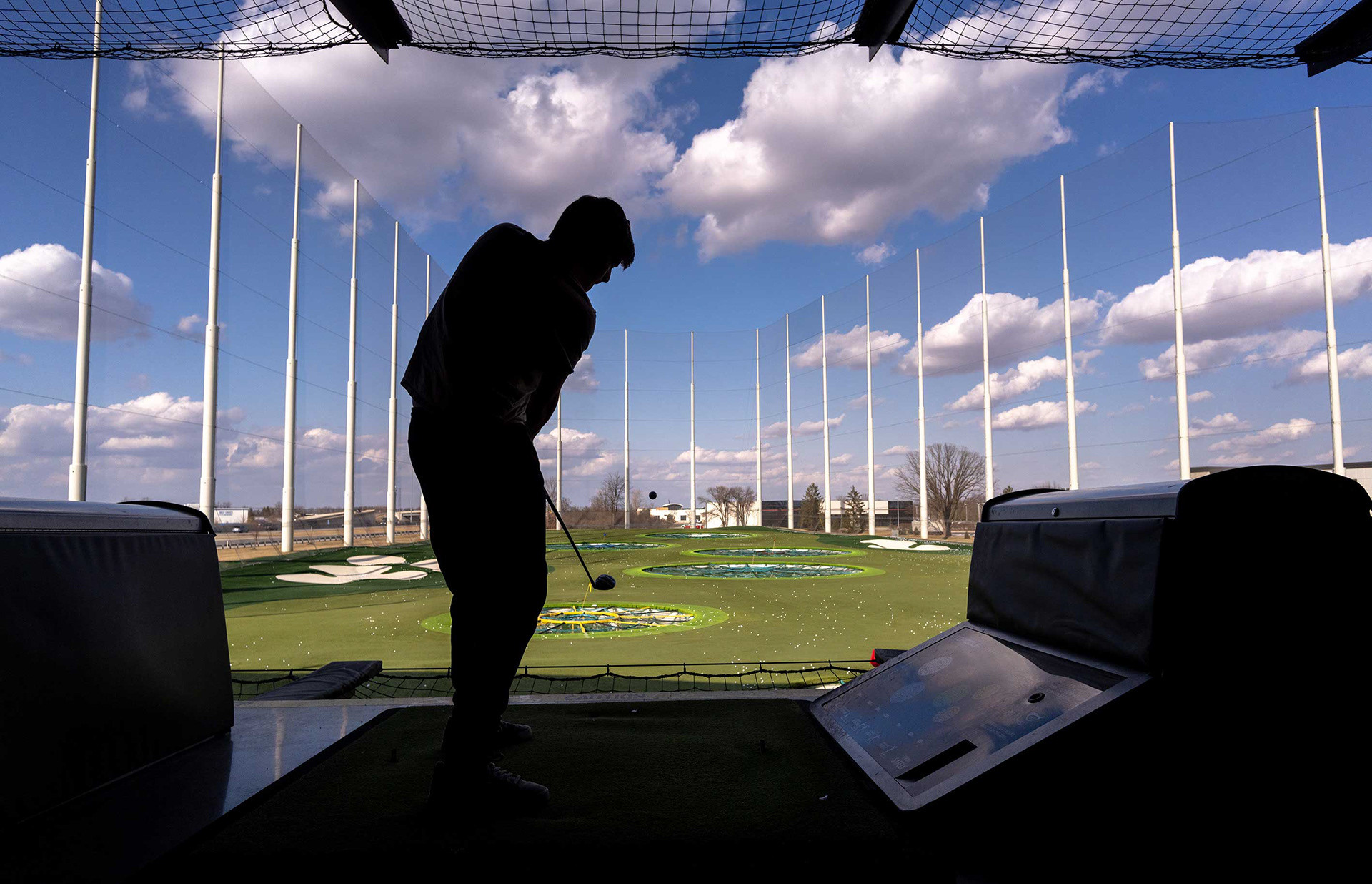 A driving range patron sends a golf ball flying.