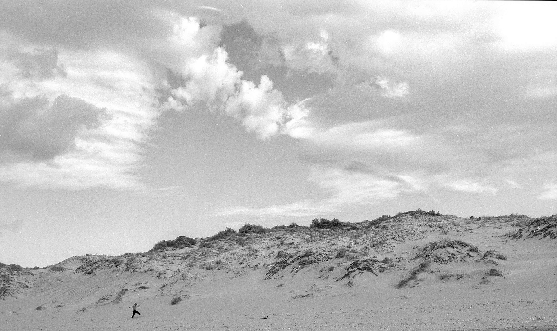 A child plays in sand dunes.