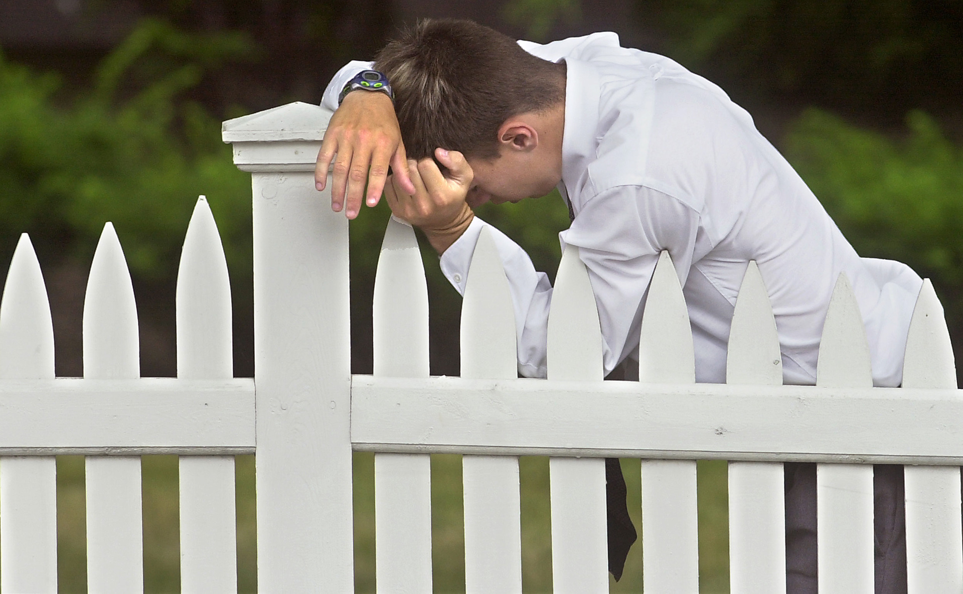 Overcome by emotions, a young man finds a secluded place on the front lawn of St. Mary's Catholic Church in Plymouth to reflect during the funeral of a murdered classmate.