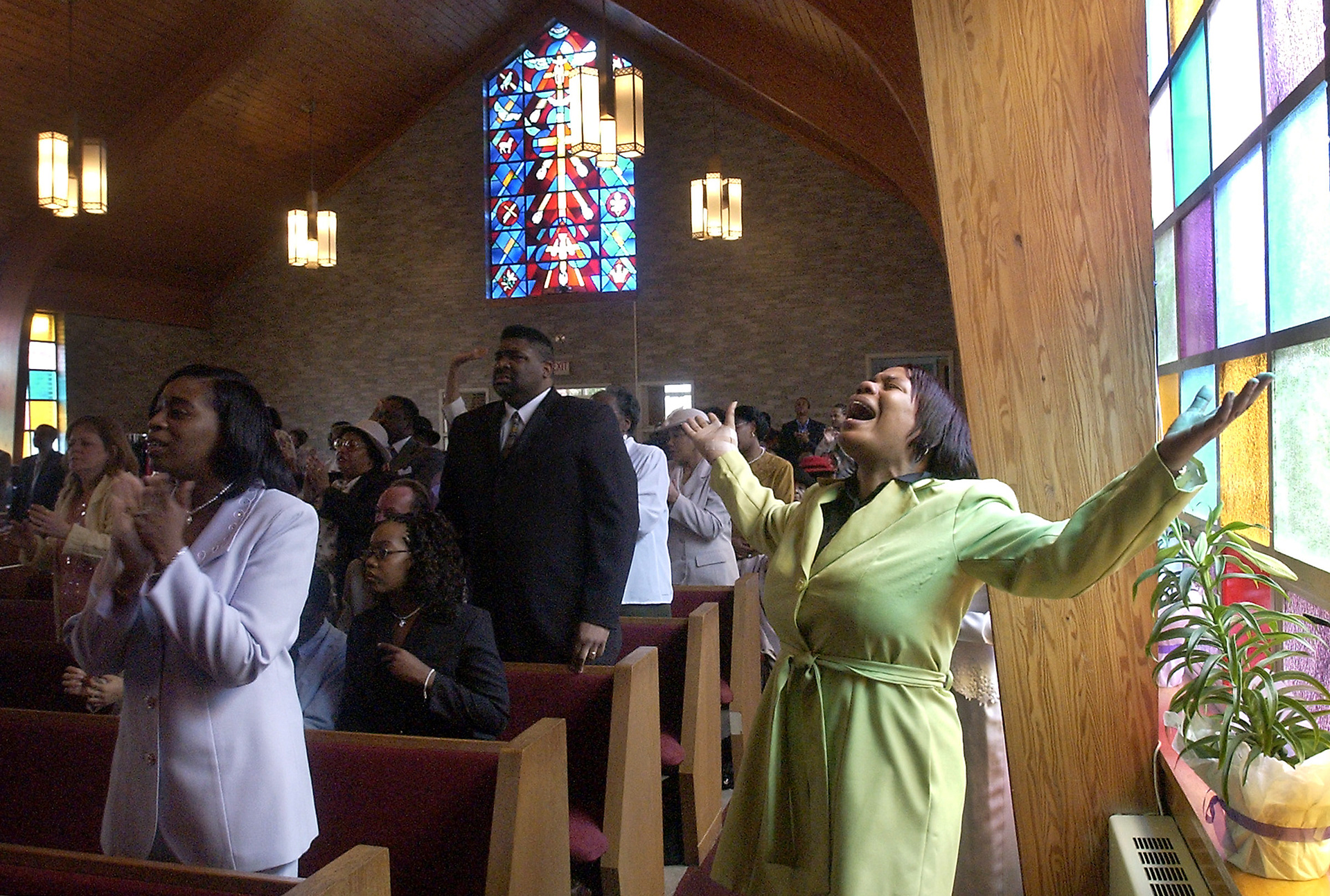 Deborah Murray, right, of Brockton lifts her hands up as she sings along with the choir during Easter Sunday service.