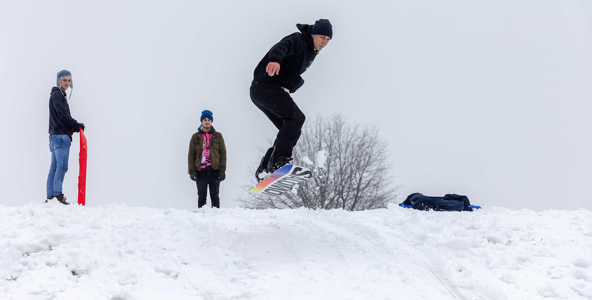 Students sled and snowboard on campus.