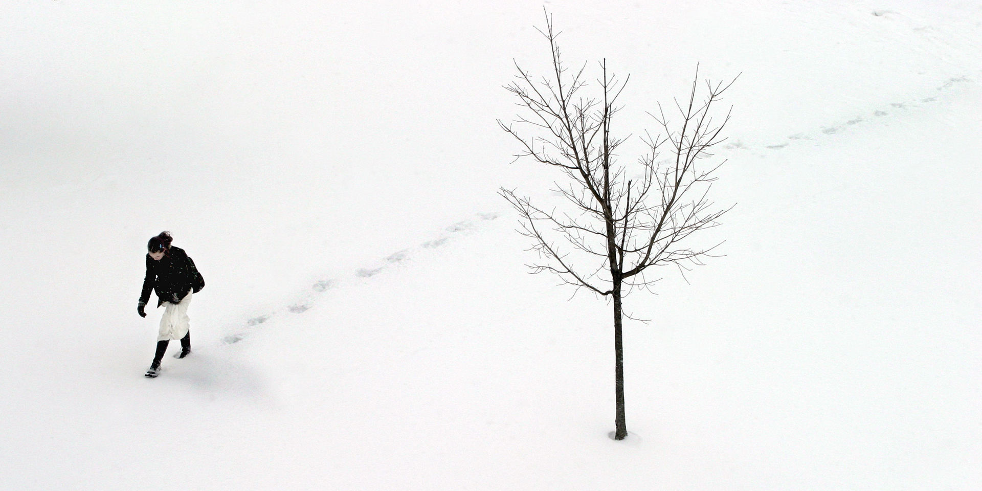 A student walks across the snowy landscape of Indiana University.