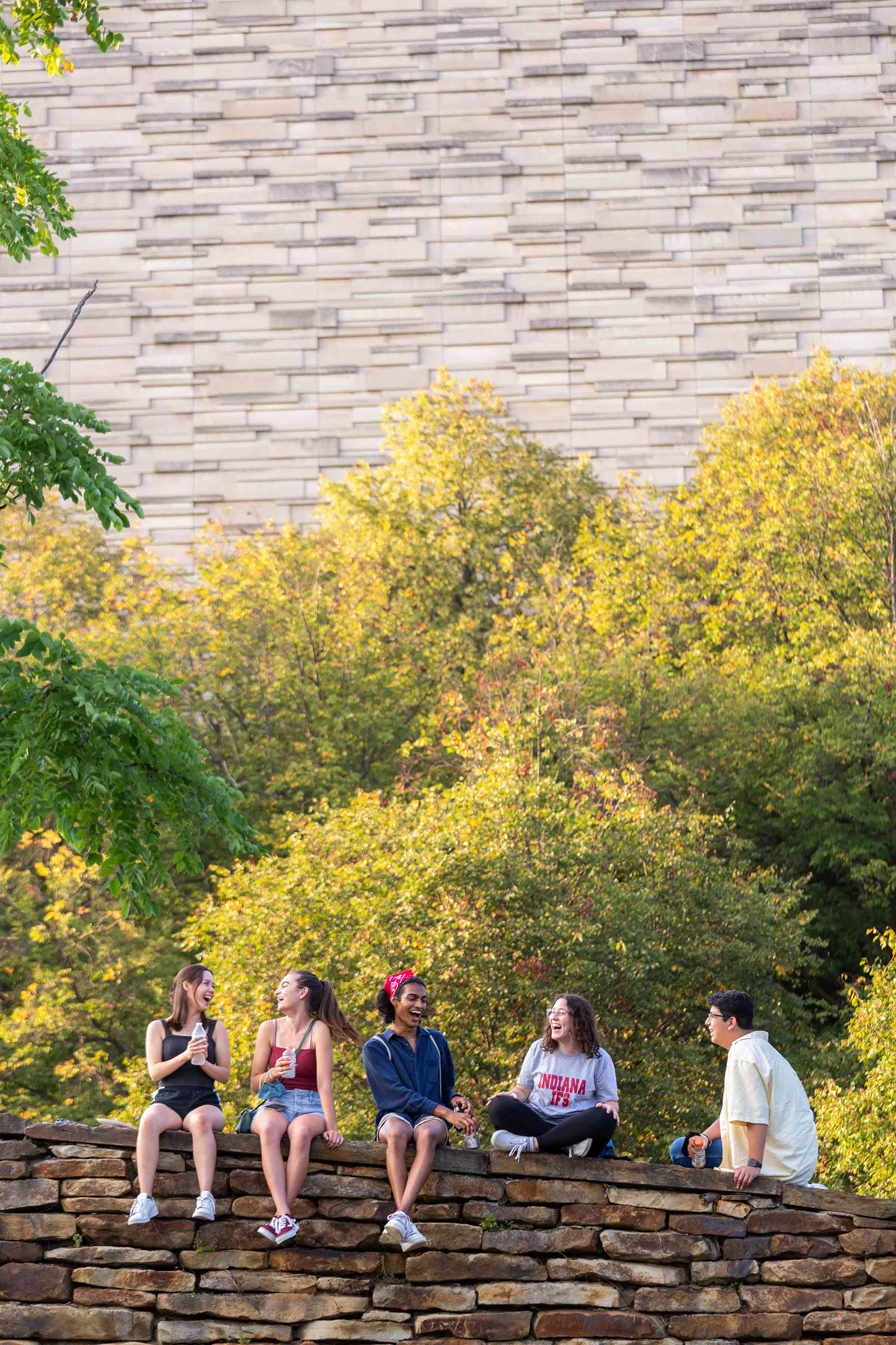 Students gather on a wall near the library.