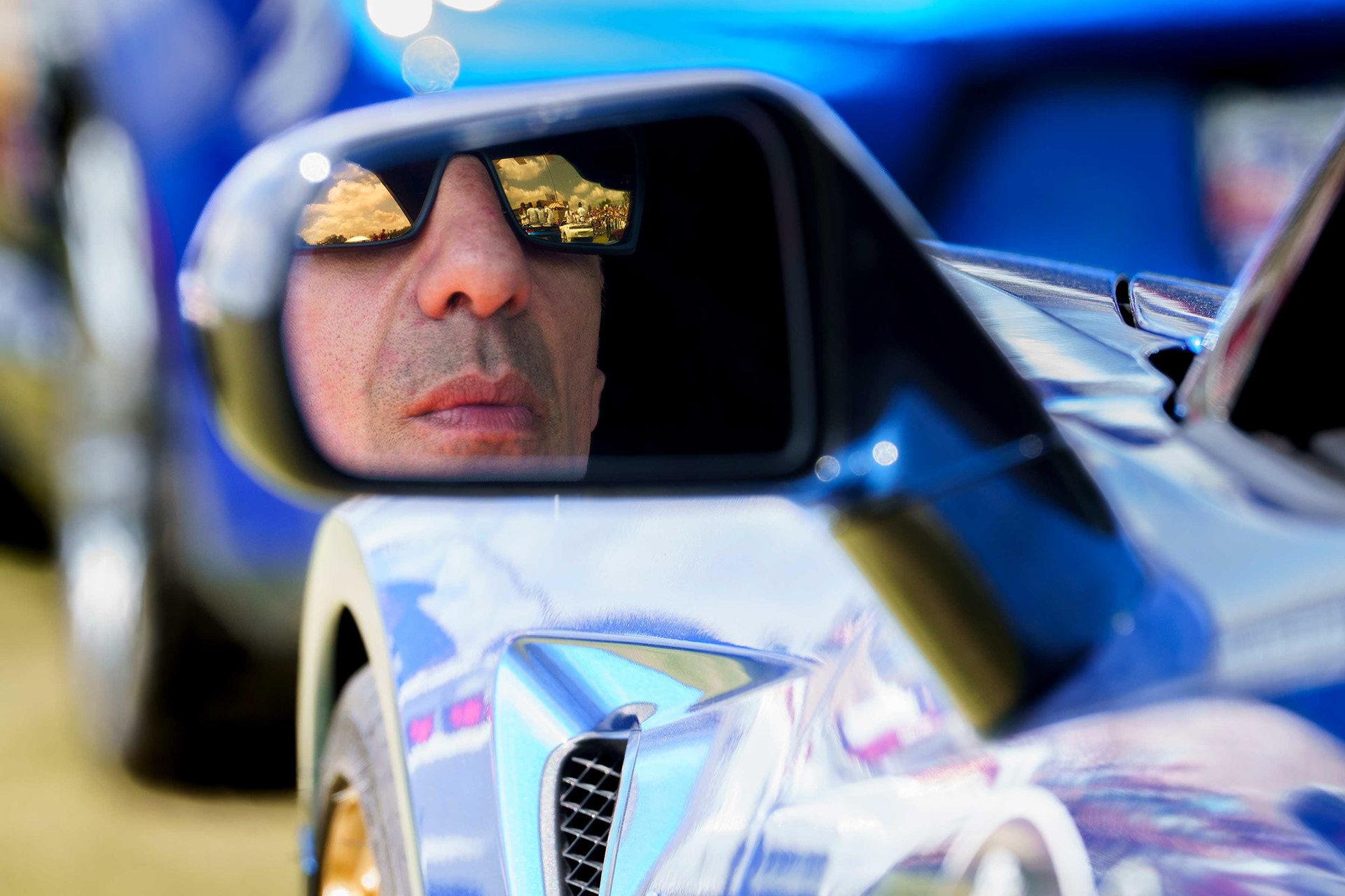 Retired race car driver Tony Kanaan is reflected in a side view mirror.