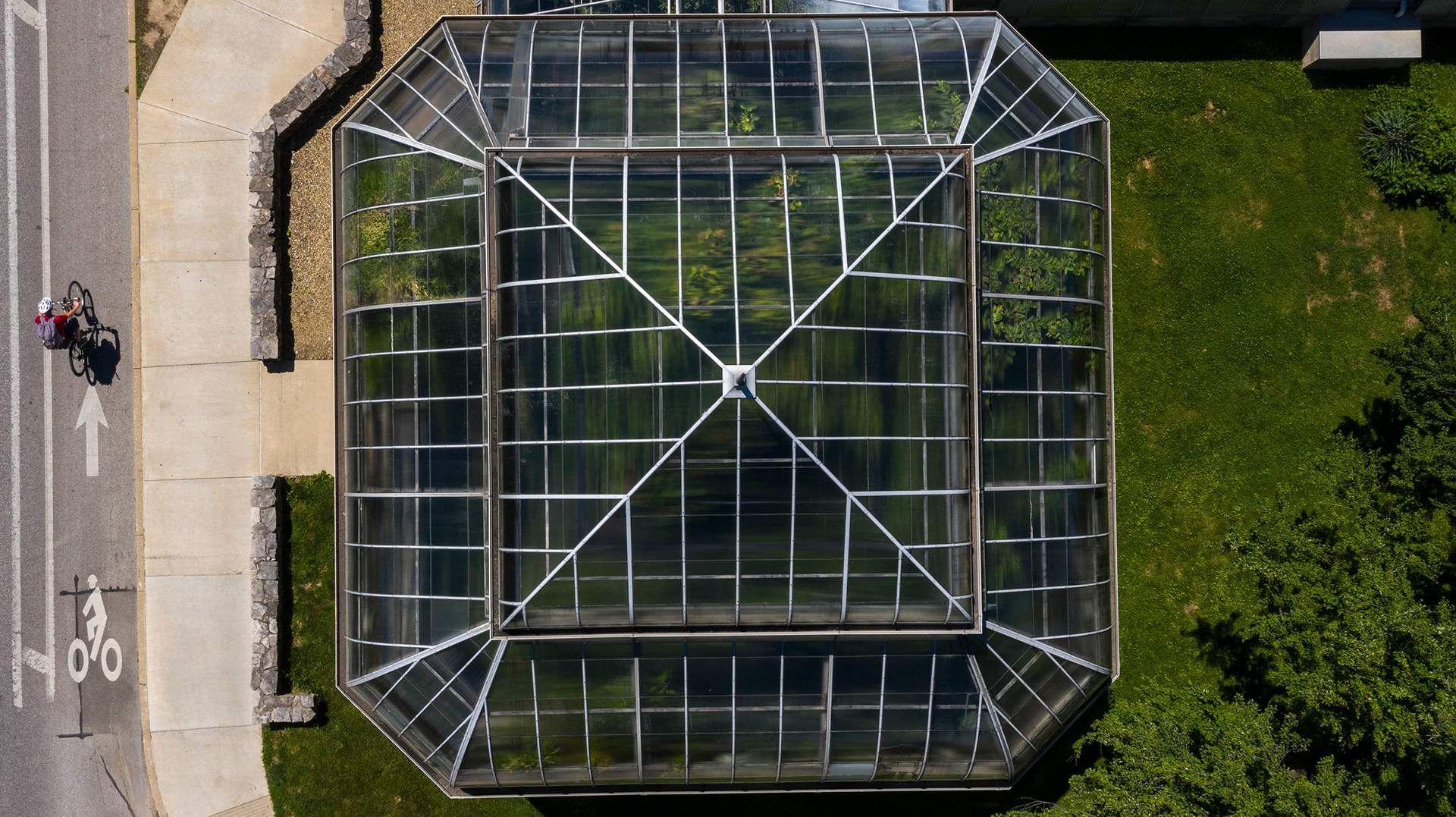 A cyclist passes the biology greenhouse at IU.