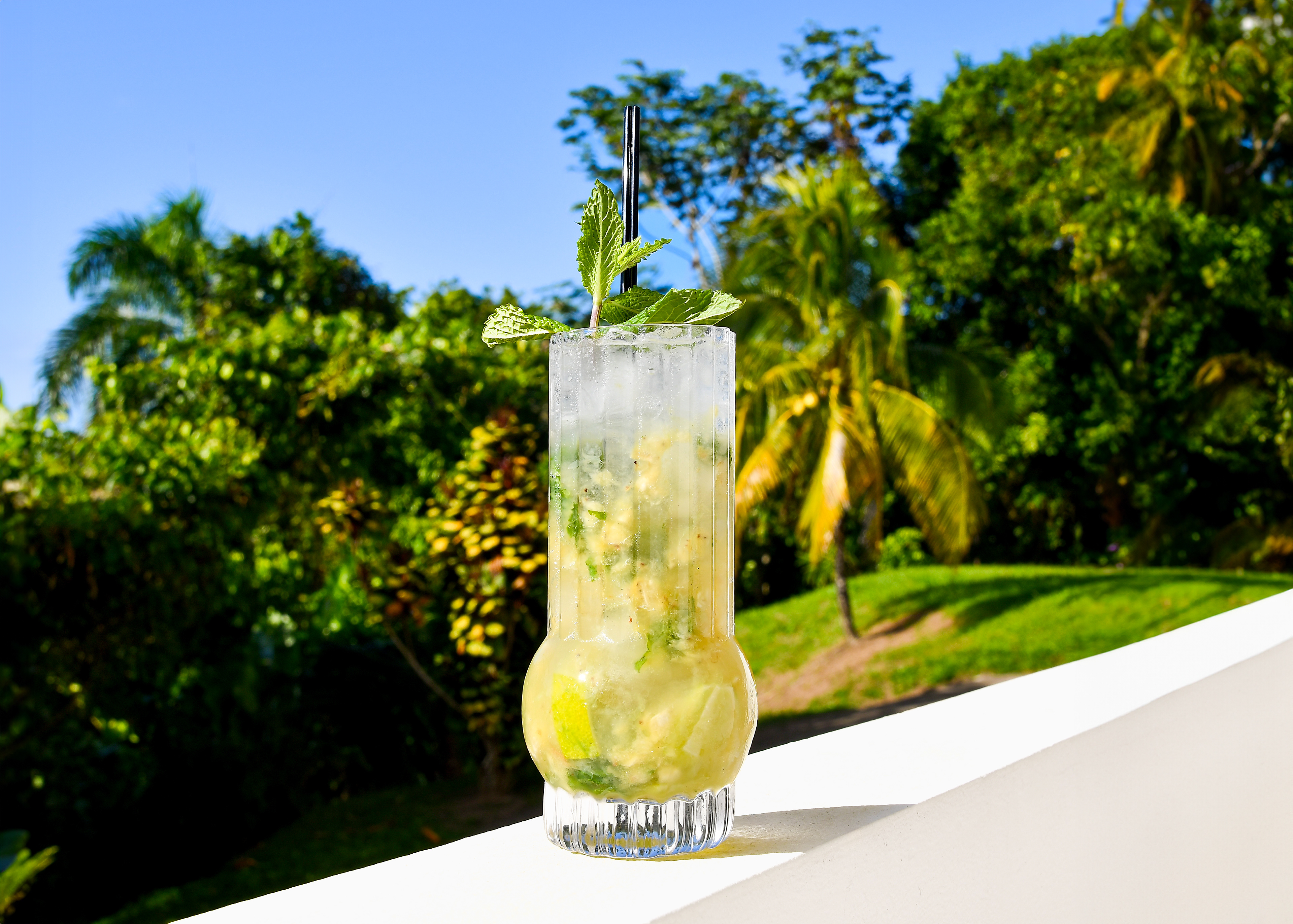 A refreshing Banana Mojito served on the west balcony of Hacienda Eterna Primavera, with a beautiful sky before sunset and lush banana grove in the background, perfect for enjoying the last moments of daylight.