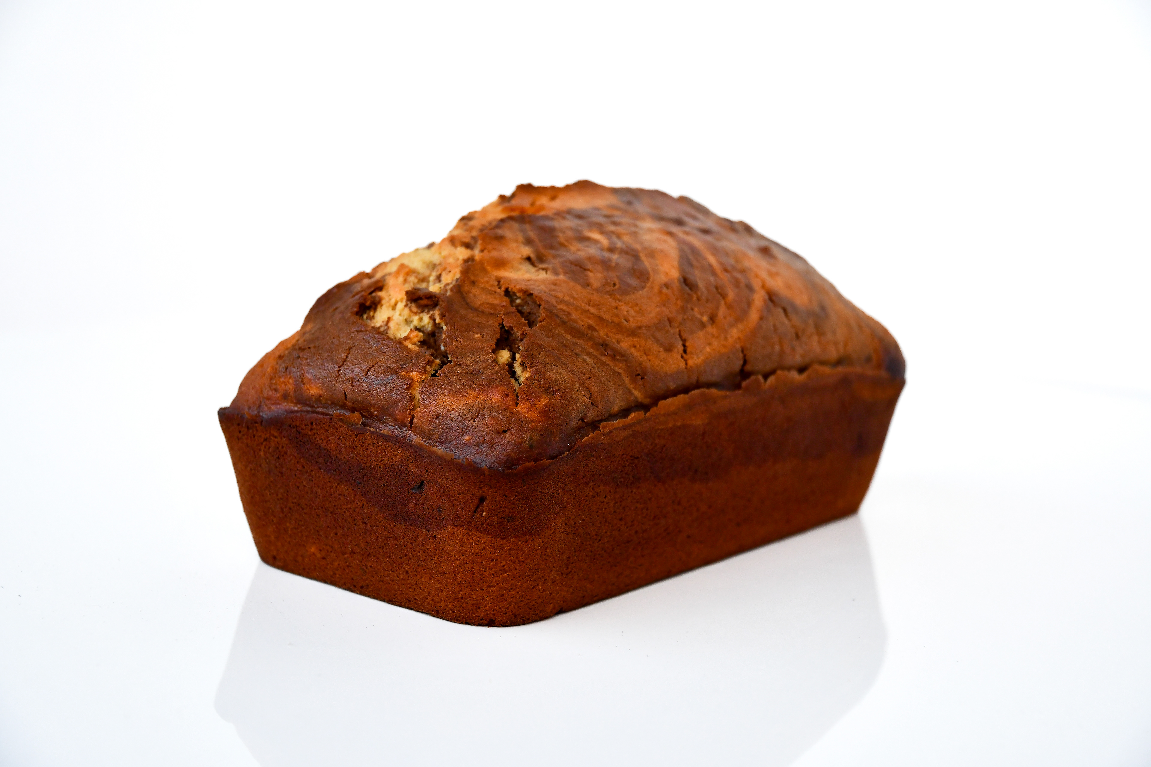 A full loaf of homemade marble cake, showcasing a golden, crispy crust and a soft, swirled vanilla and chocolate interior. The cake sits on a wooden surface, highlighting its rich texture.
