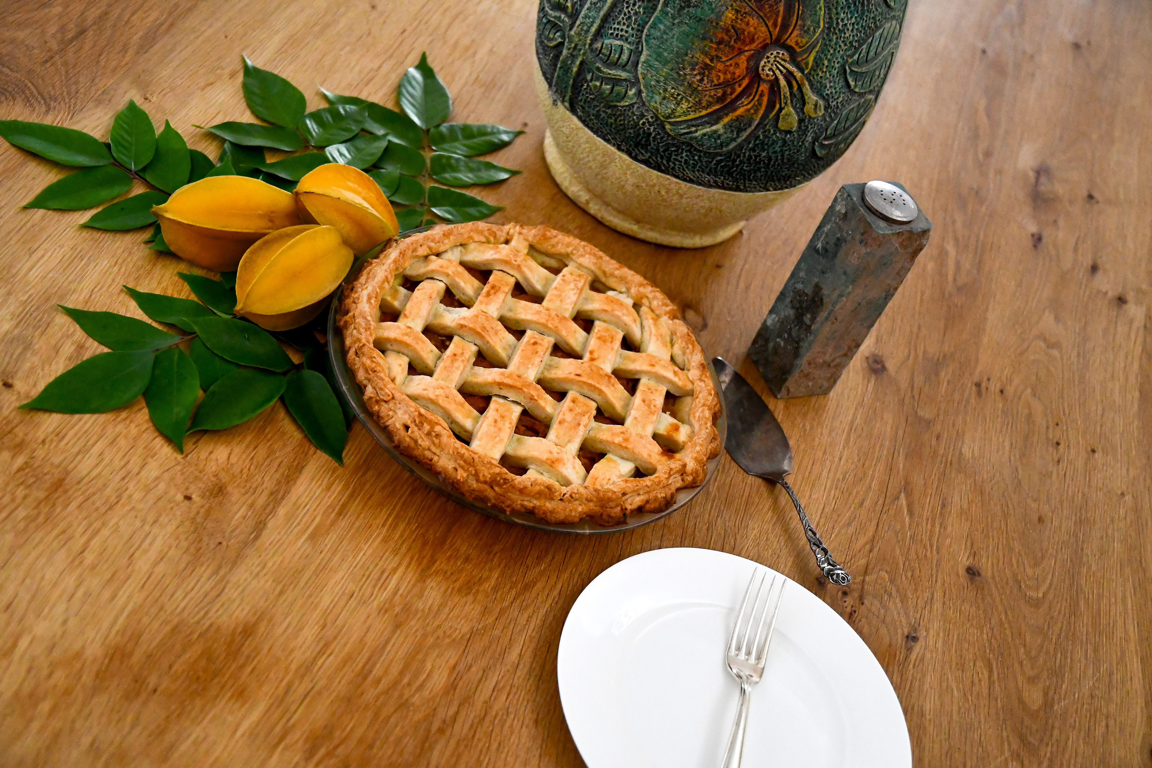 A whole, freshly baked starfruit pie with a golden, flaky crust sits on a rustic wooden table at Hacienda Eterna Primavera, made from starfruits grown on the hacienda’s land.