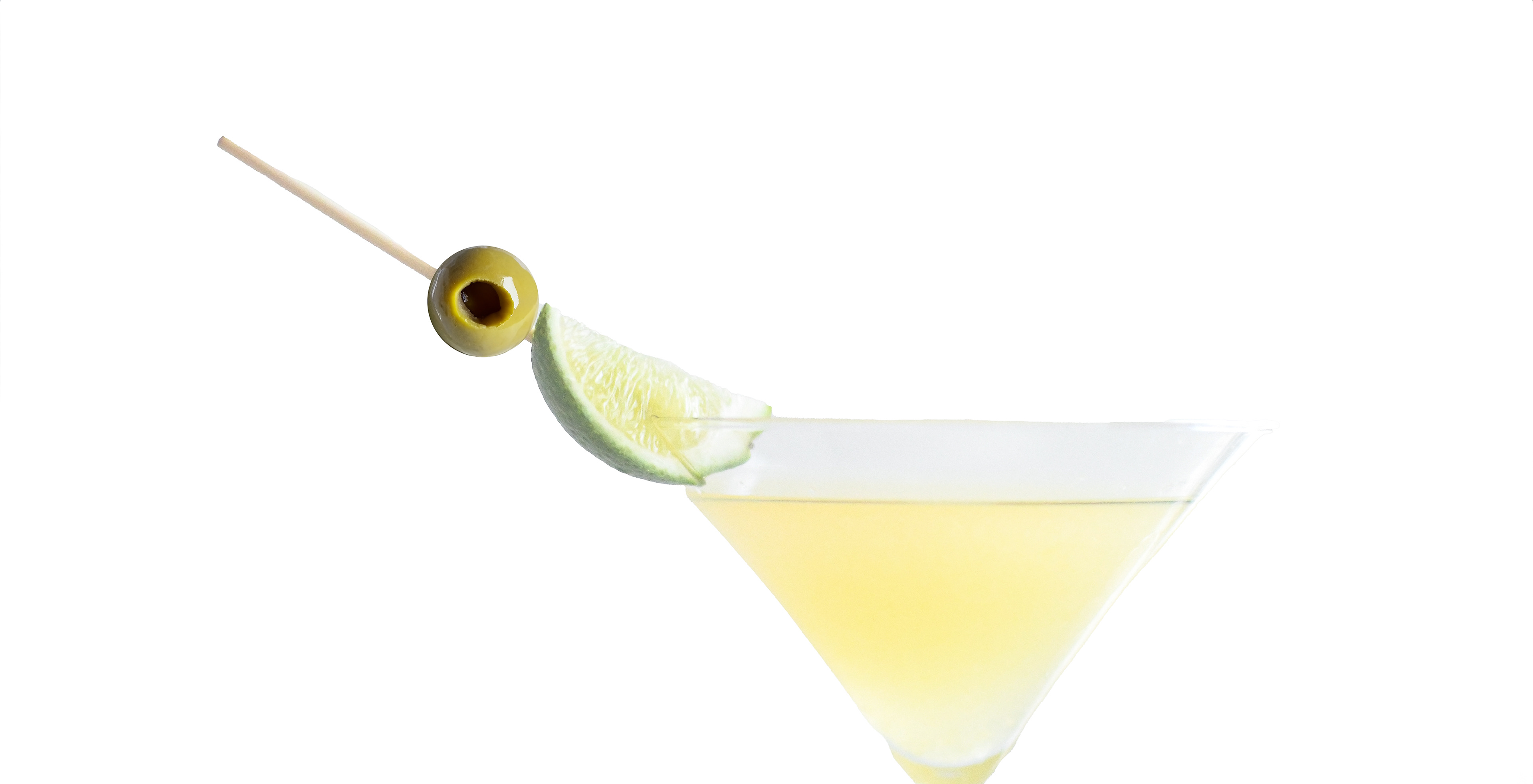 Mexican Martini Close-Up: A clear glass filled with a Mexican Martini, garnished with an olive and lime wedge, sitting on white background