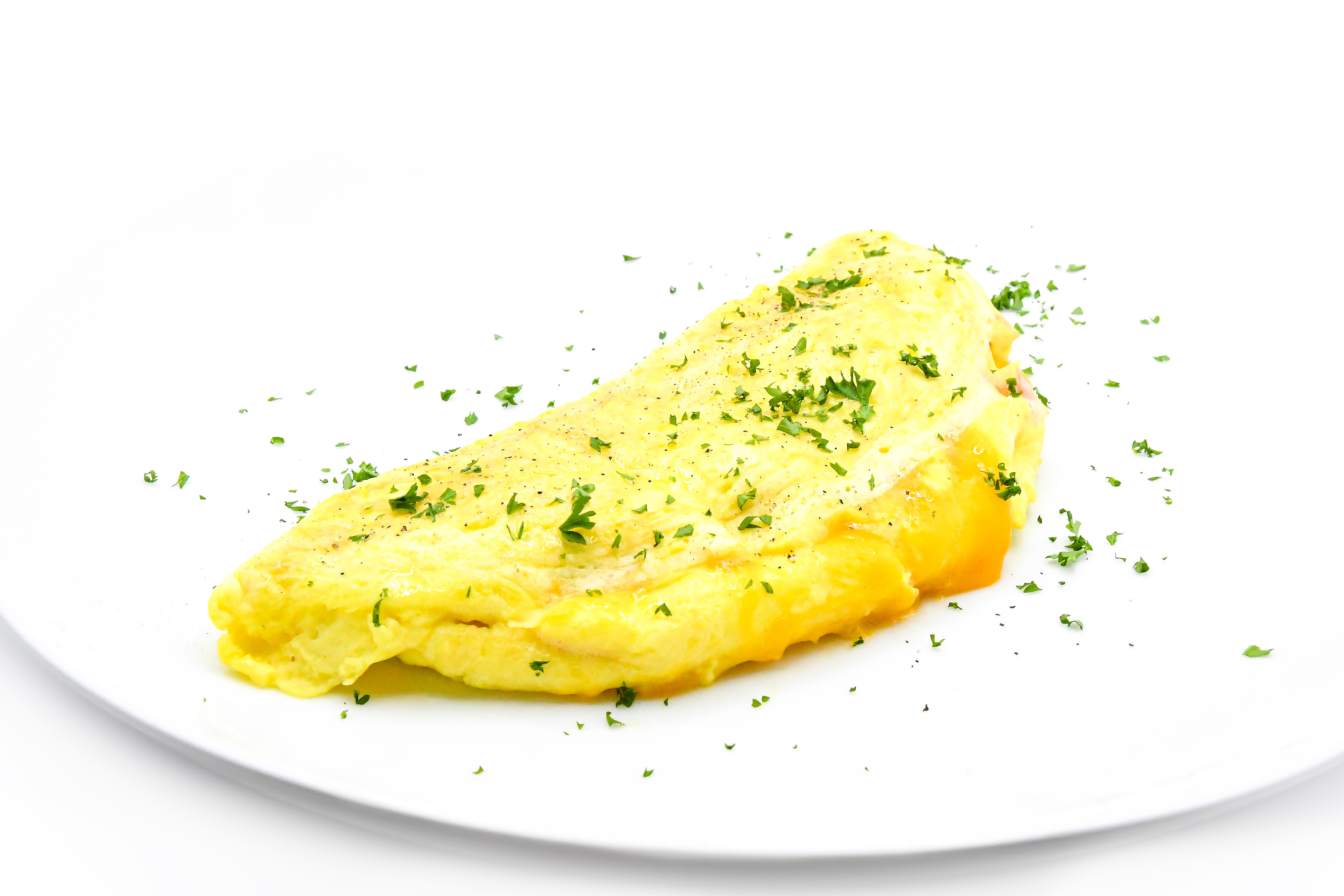 Image of a fluffy omelette on a white background. The omelette is golden in color and perfectly folded, with melted cheese visible in the middle. A sprinkle of herbs adds a pop of green to the dish