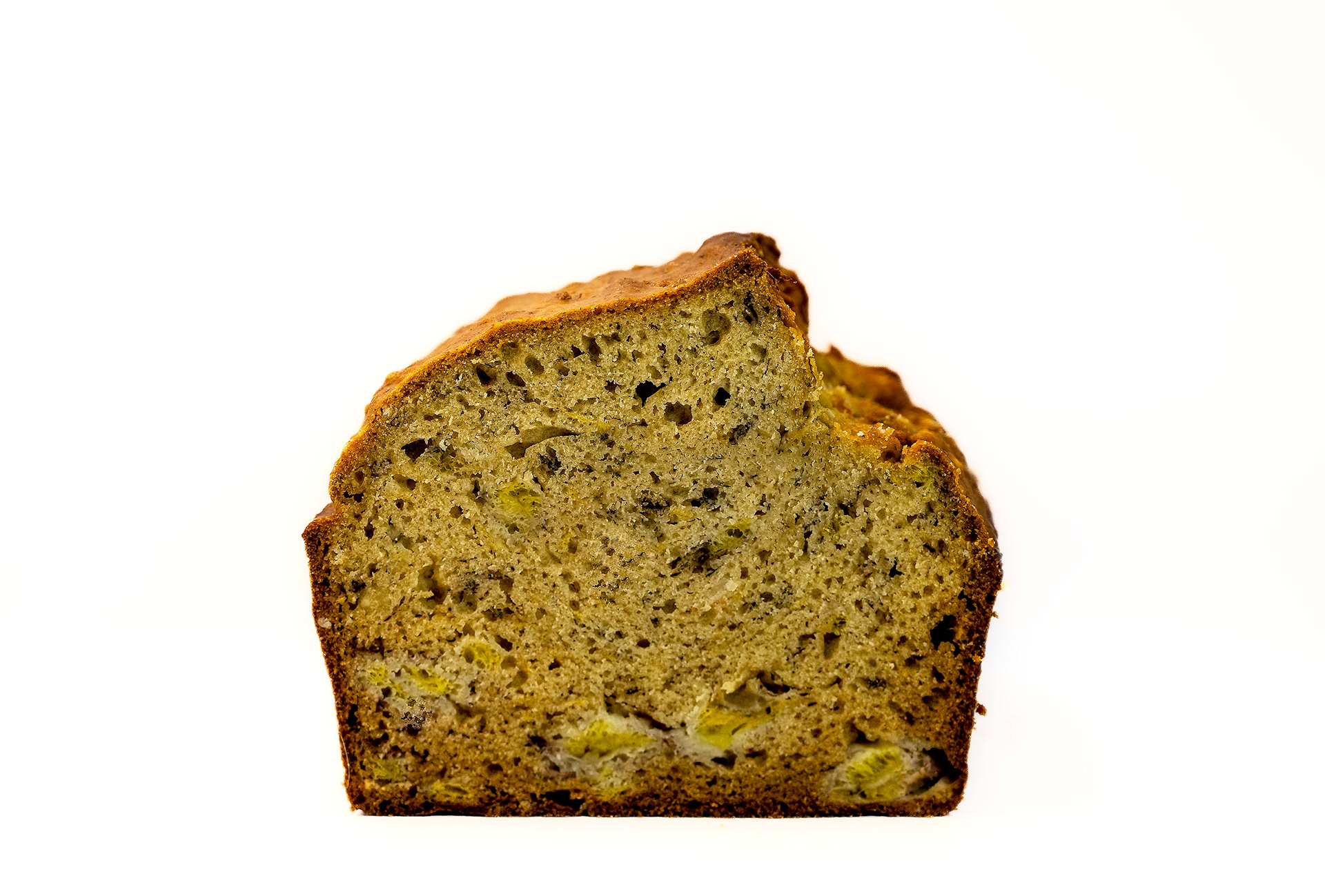 Golden-brown loaf of banana bread displayed on a white background. The bread has a slightly domed top with a crack running lengthwise, showcasing its soft and moist interior. The surface is dotted with specks of caramelized banana and hints of spices, giving a rustic, homemade look.