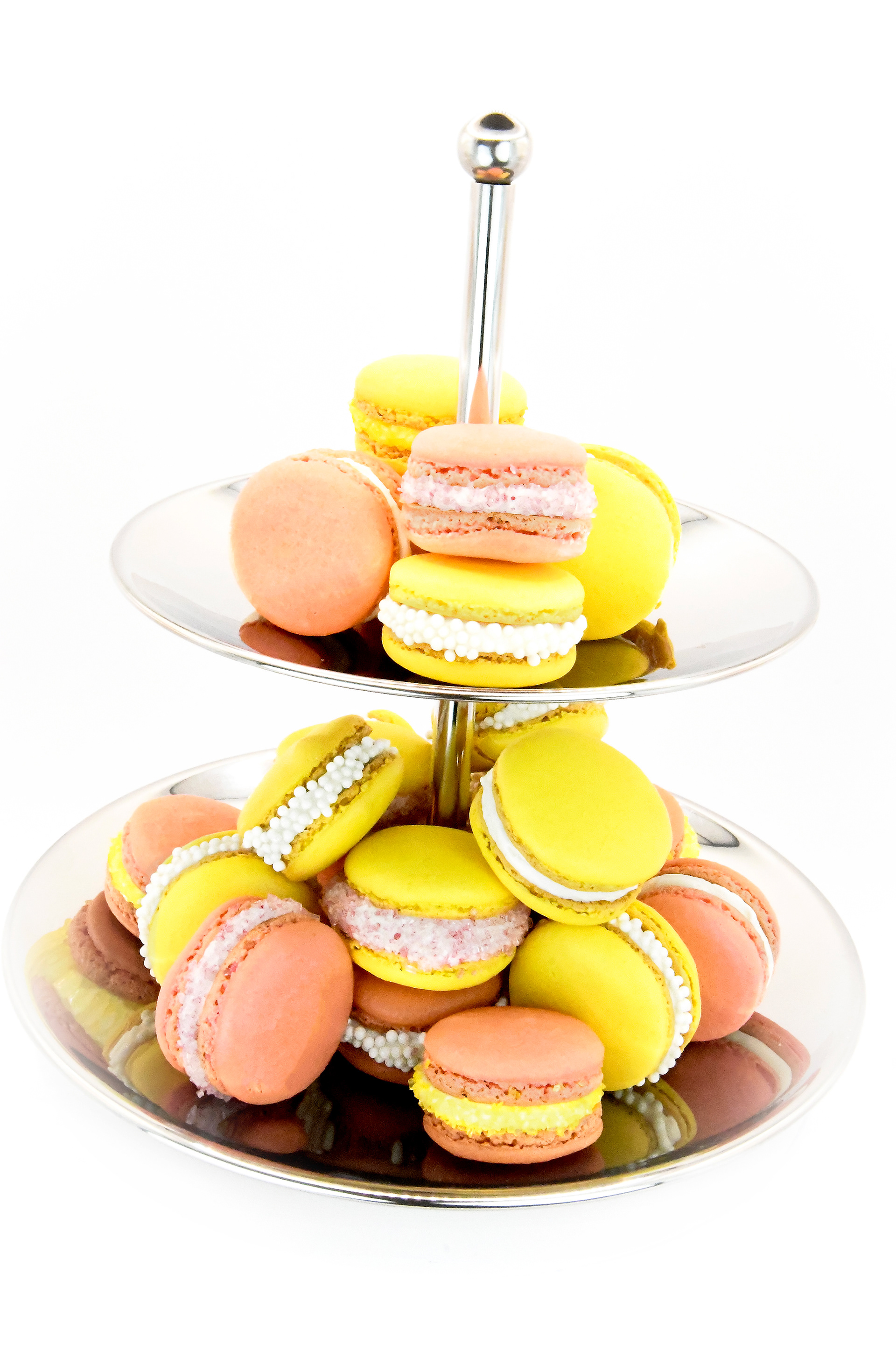 COLORFUL FRENCH MACARONS (YELLOW AND PINK) WITH A WHITE BUTTER CREAM FILLING ON NICELY DECORATED ON A ETAGERE WHITE BACKGROUND