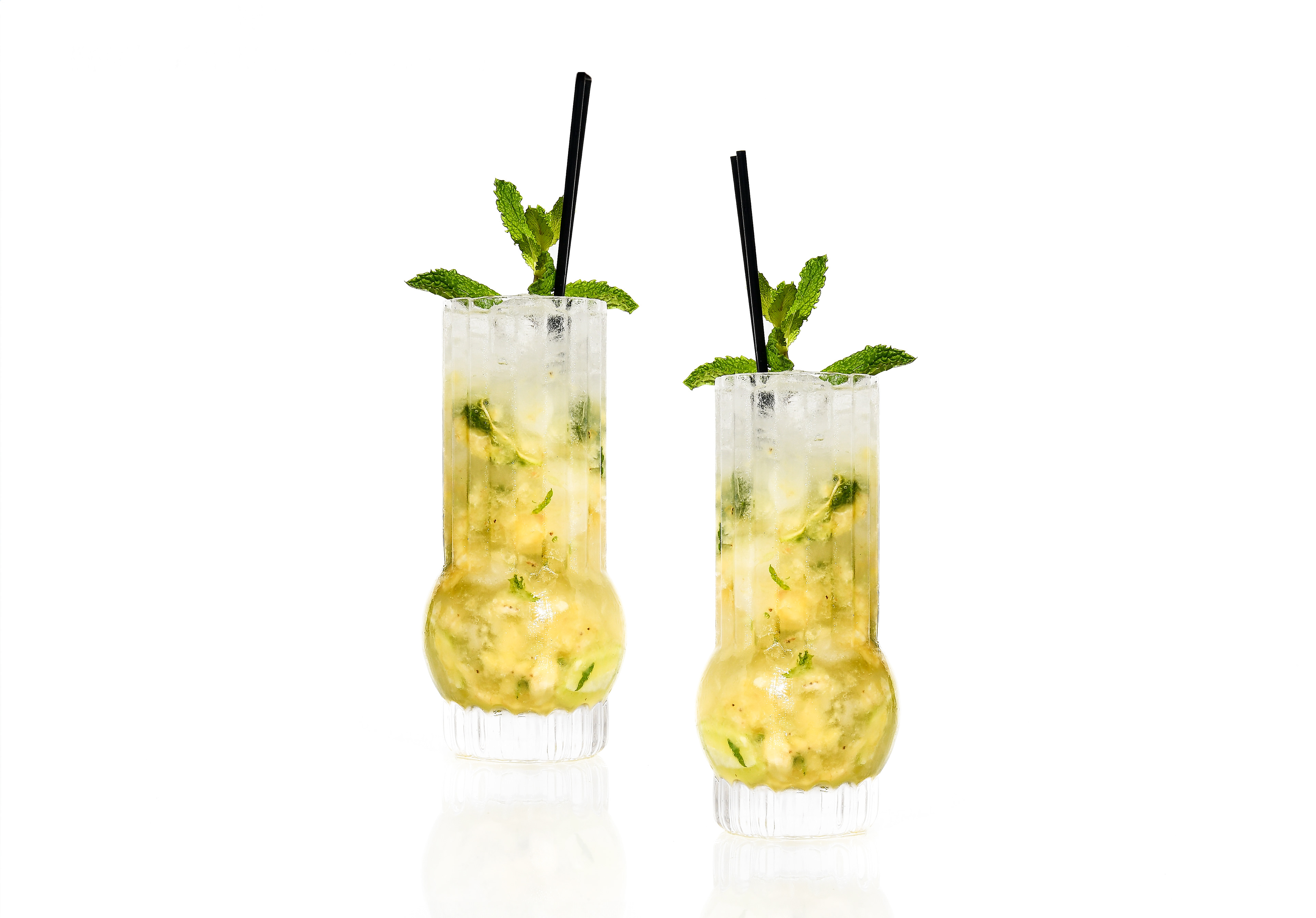 Two Banana Mojito cocktails on a white background, garnished with fresh mint leaves, showcasing the tropical drink made with ripe banana, mint, and lime.