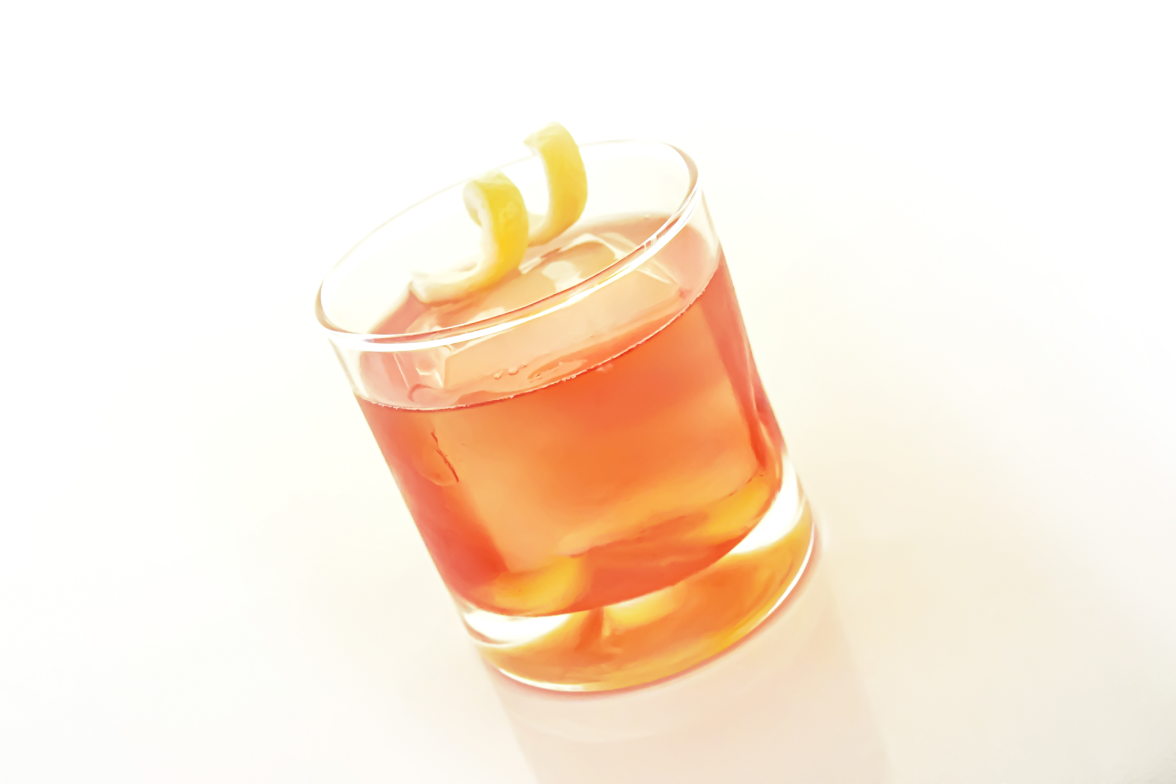 A close-up of a Negroni cocktail on a white background. The rock glass features a large square ice cube, with the classic Negroni ingredients—gin, sweet vermouth, Campari, Angostura Bitter, and filtered water—perfectly balanced and stirred to chill. The drink is garnished with a twist of lemon peel, which has been twisted over the glass and rubbed on its rim for added flavor. The image highlights the rich color and refined presentation of this timeless cocktail.
