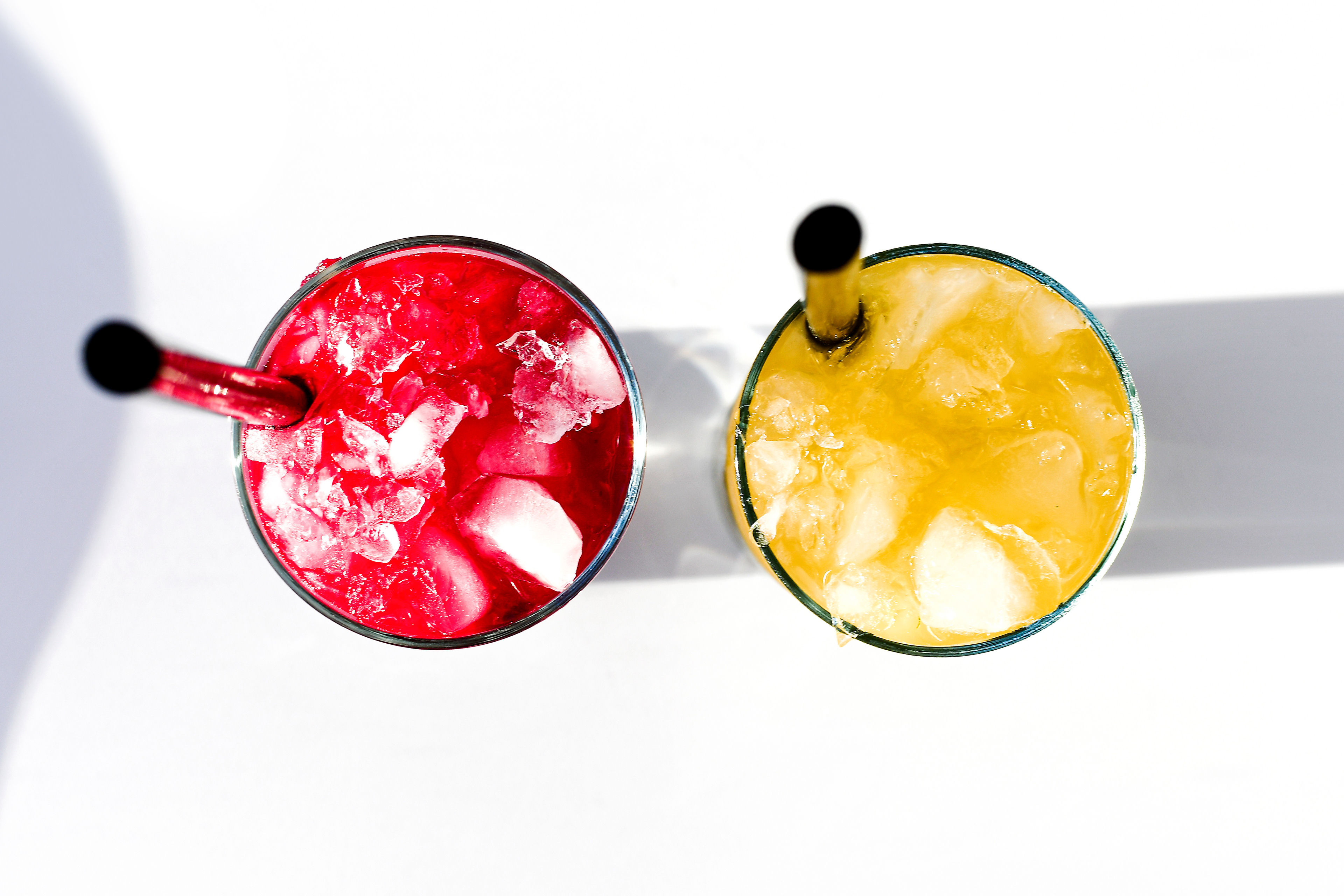 A top-down view of two vibrant glasses of Beet Mojito, one red and the other yellow, standing side by side with no garnish or straw, showcasing their rich, popping colors. The drinks are a unique twist on the classic Mojito, featuring a refreshing blend of beet juice, rum, lime, and mint. The bright colors and fresh ingredients make these Beet Mojitos visually striking and full of flavor, perfect for adding an unforgettable touch to any gathering.