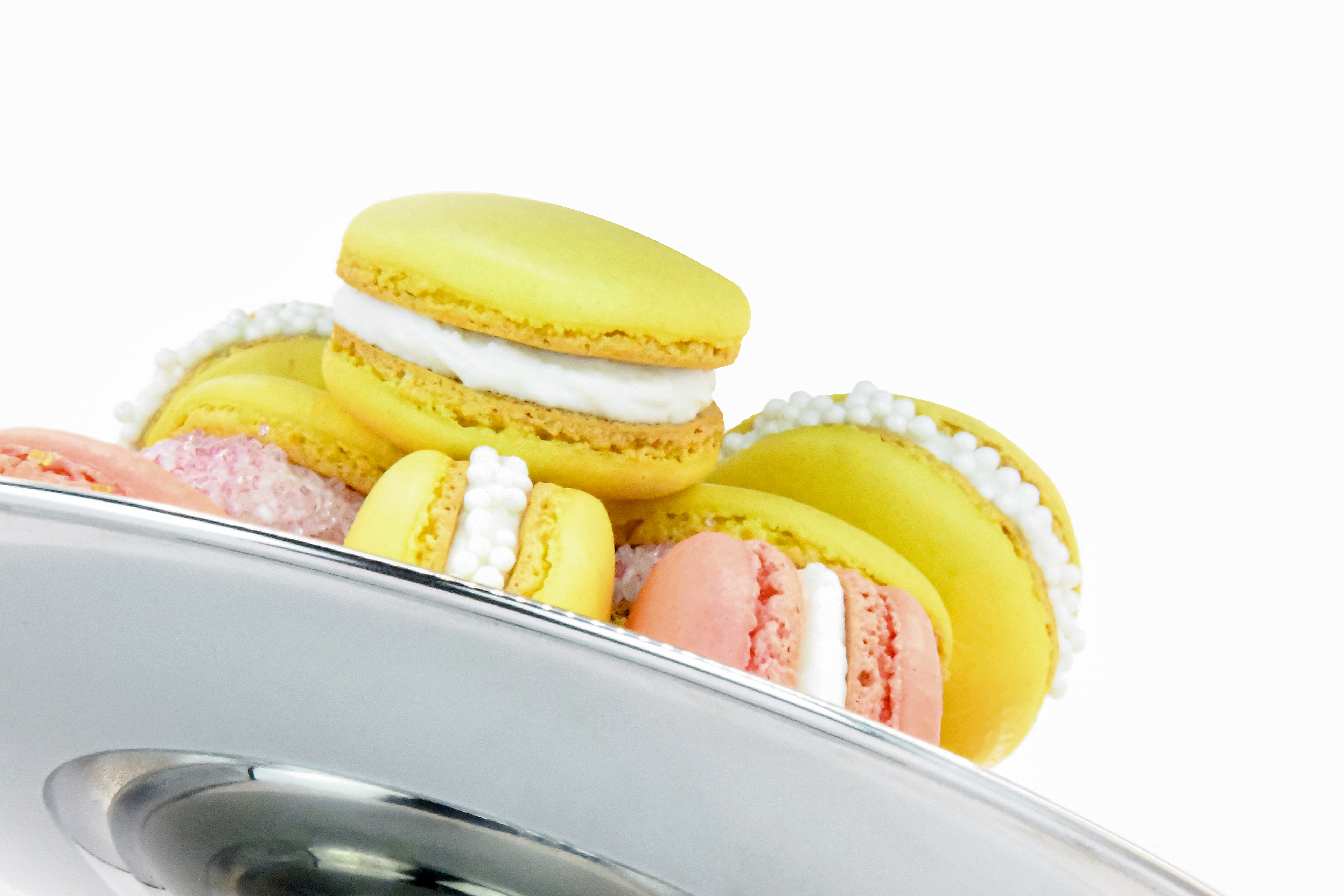 COLORFUL FRENCH MACARONS (YELLOW AND PINK) WITH A WHITE BUTTER CREAM FILLING ON NICELY DECORATED ON A ETAGERE WHITE BACKGROUND