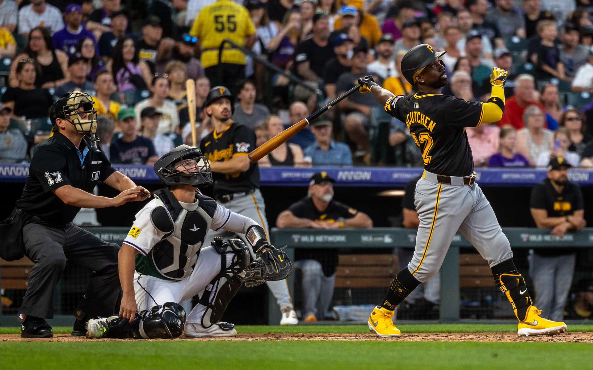Pittsburgh’s Andrew McCutchen admires his swing at Coors Field as players, fans, and the umpire all watch the ball soar. The deep drive carried into the Denver night, a reminder of McCutchen’s enduring power at the plate.
