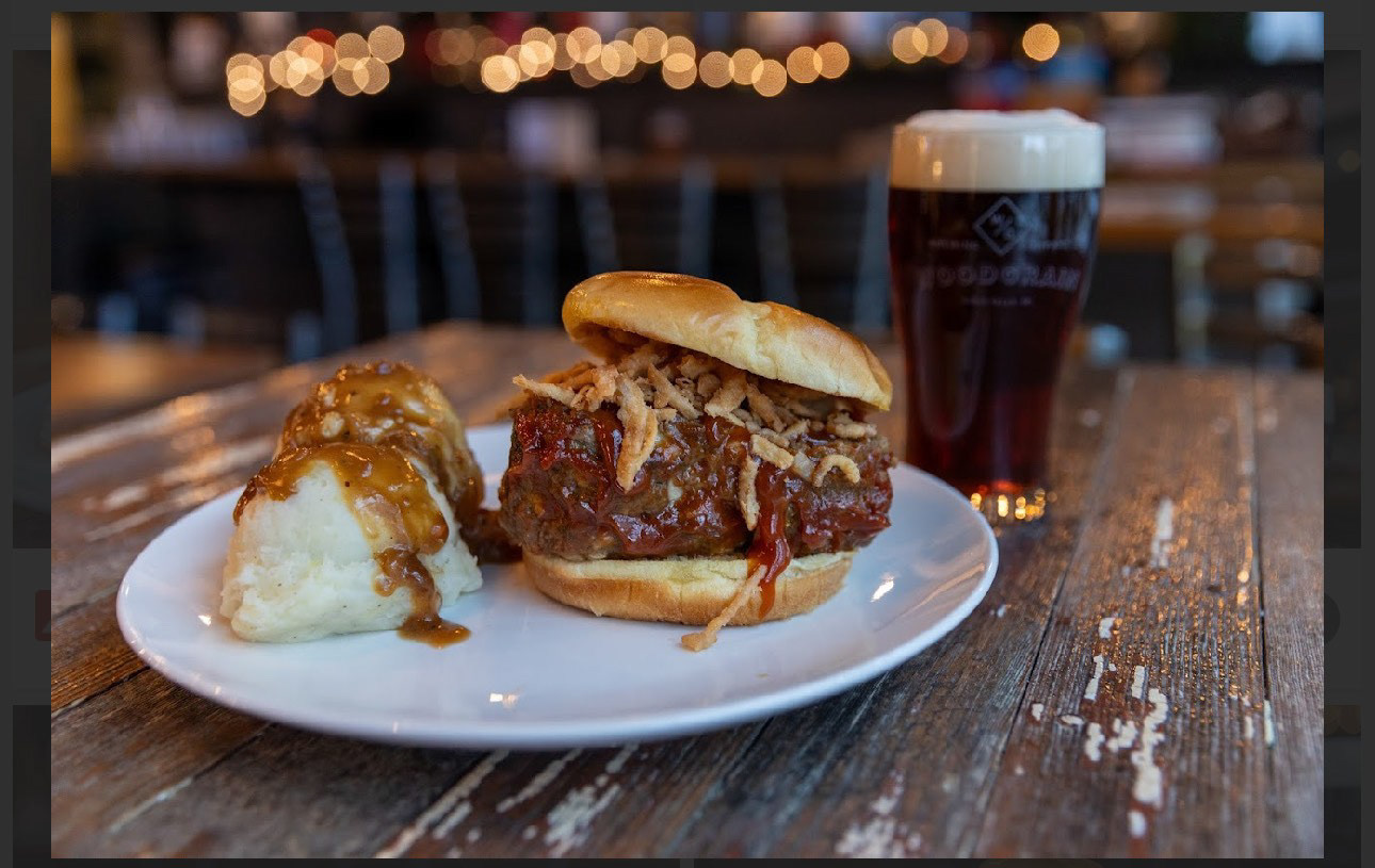 We Smoked Mom's Meatloaf Burger - Woodgrain Brew Co feat. So. Perf. BBQ - 8oz patty mixture of freshly ground chuck, secret meat loaf stuffins, and house made smoke brisket tallow. It is then topped and smoked with Southern Perfection BBQ’s Special Meatloaf Sauce. The Meatloaf Burger is slathered with a second coat of the special sauce, sprinkled with fried onions, and placed between a toasted Brioche Bun.  A warm side of triple creamed mashed potatoes accompanies our burger with a side of homemade gravy drizzle!  