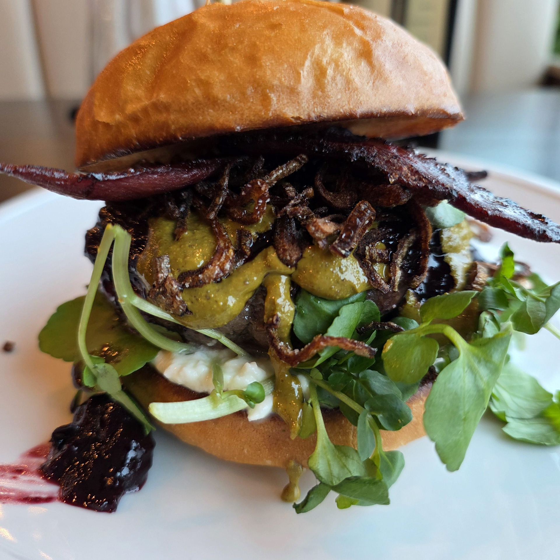 Wapiti Butter Jelly Time! - Rivage Oak Kitchen - Elk burger with watercress, chokecherry compote, duck bacon, blue cheese, pistachio butter, and fried shallots served on a shockupan bun. 