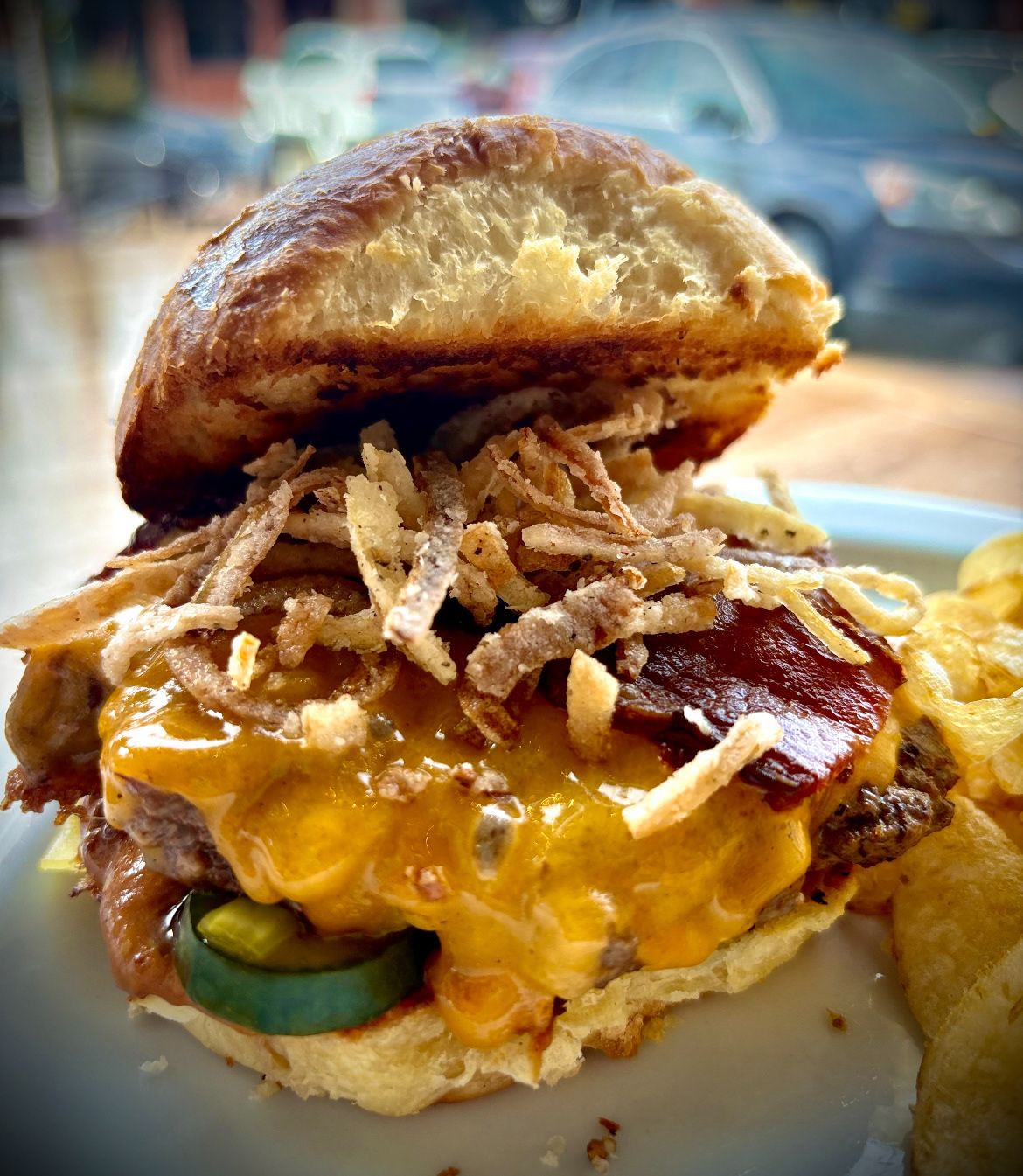The Giddy Up! Burger - M.B. Haskett's - A 5 oz beef burger with Widmer's aged cheddar, bacon, tobacco onions, sweet & spicy pickles, and Carolina yellow barbecue mayo on a brioche bun.  Server with a side of chips. 