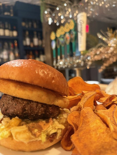 The MANGhOst Burger - Ode to Food & Drink - 7 oz House Ground Wagyu Beef Blend grilled to order on a brioche bun with Mango Aioli, Fried Ghost Pepper Cheese and Jalapeno Bacon Slaw served with your choice side {fries, sweet potato chips, roasted sweet potatoes, garlic mashed potatoes, cucumber salad, garden salad, ceasar salad, or soup 