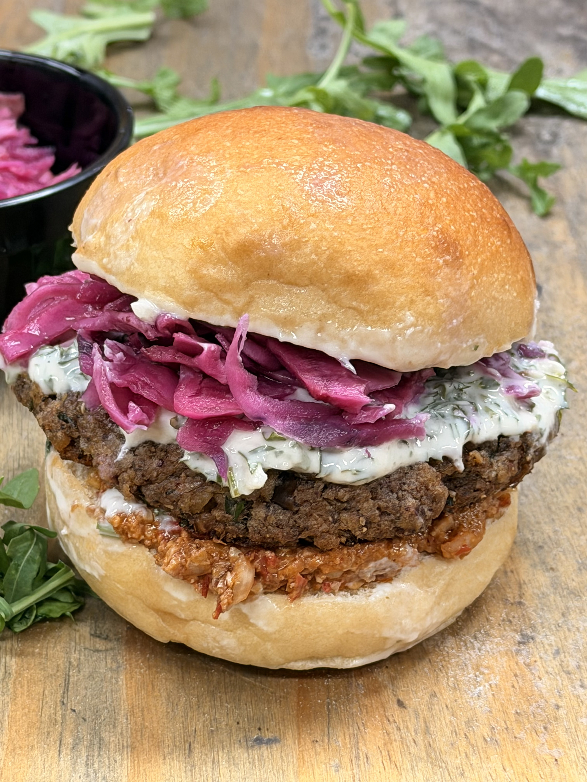Smoky Walnut & Herb Vegan Burger -  Sanaa's Gourmet Mediterranean - A smoky, savory patty made with roasted vegetables, toasted walnuts, mushrooms, and warm spices. Crispy on the outside and tender inside. Served with muhammara, tahini-parsley sauce, and pickled cabbage. Comes with rosemary roasted potatoes and salad.