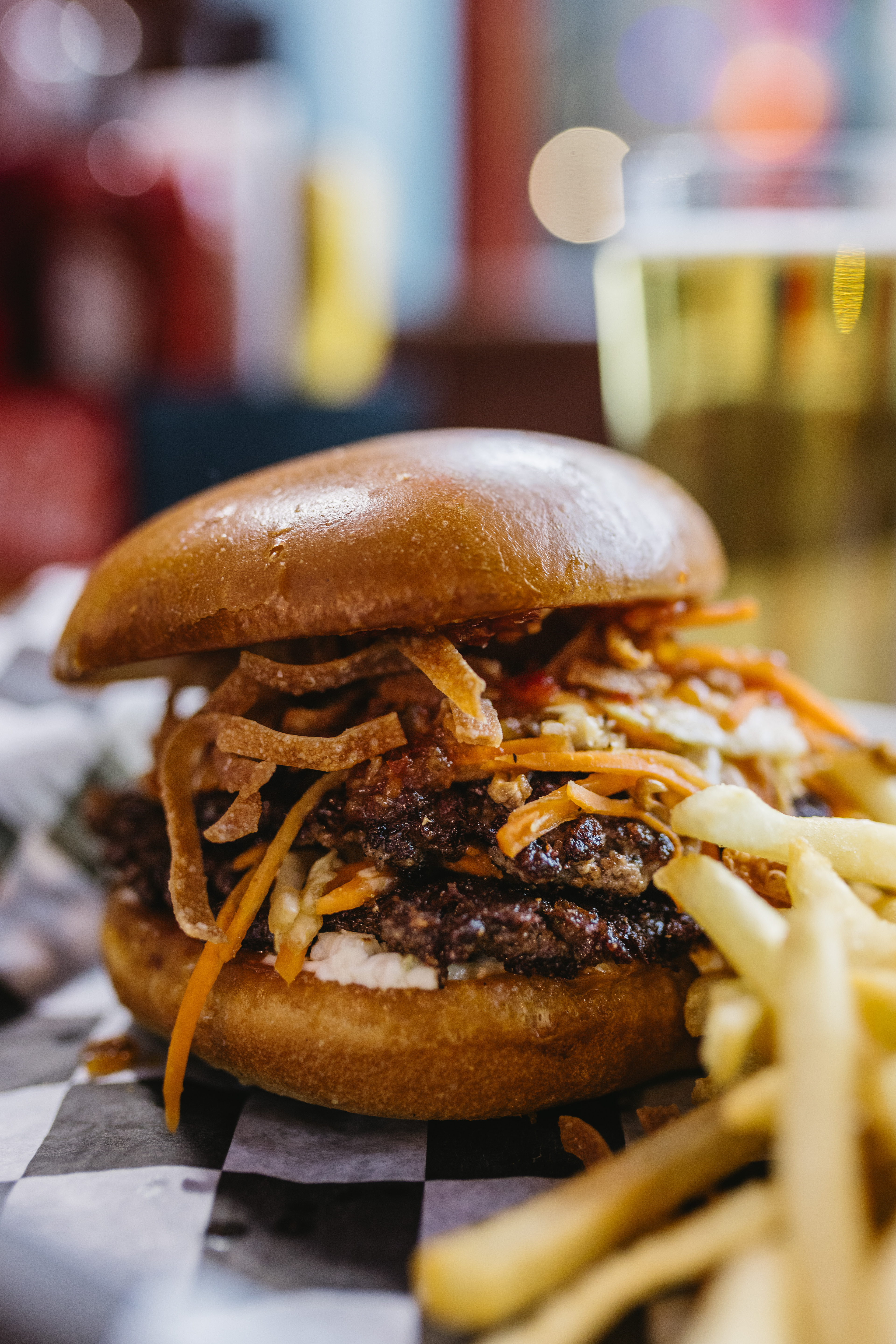 Spring Roll Showdown - Big Sioux Burger - All the crunch of a spring roll, supercharged with beef. Two seasoned smash patties stack up on a soft hamburger bun smeared with sweet chili cream cheese. Our hoisin-infused spring roll veggie blend of carrots, cabbage and mushrooms brings the crisp and the color layered between the patties and piled on top. Finished with fried wontons and a sweet-chili drizzle, this burger doesn’t just enter the battle… Two patties. One crunch. Total domination.