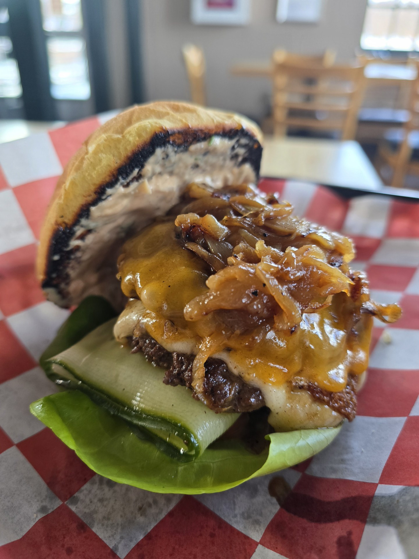 The Sioux Smash Burger -  Falls Overlook Cafe - Double smash patties made from a rich blend of bison, chuck and brisket, perfectly seasoned with our signature Umami seasoning for deep, savory flavor. Topped with melted mild cheddar and Gruyère, caramelized onions, house-marinated pickles, crisp lettuce, and fresh tomato — all stacked high on a toasted potato bun and finished with our homemade burger sauce. Served with a side choice.