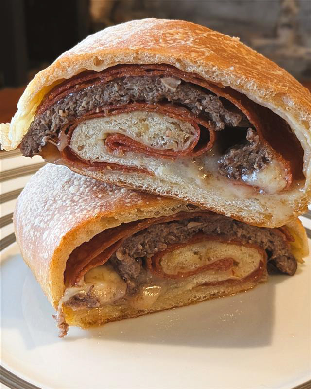 Nunzios Stromboli Burger - Nunzios- The Stromboli burger features a prime beef patty, pepperoni, and mozzarella sealed inside a warm baked crust, with your choice of Arrabbiata, Marinara, or Garlic Basil Bechamel for dipping. Served with a Caesar salad.