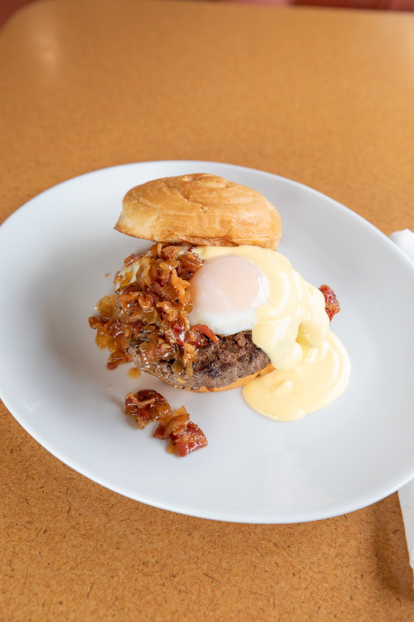 Croissant Royal Burger - Phillips Ave - Our classic diner steak burger layered with peppered bacon, sweet bacon–onion jam, a basted medium Dakota Layers egg, and rich hollandaise, all served on a warm toasted croissant bun. Comes with your choice of skillet potatoes or classic diner French fries.Diner - 