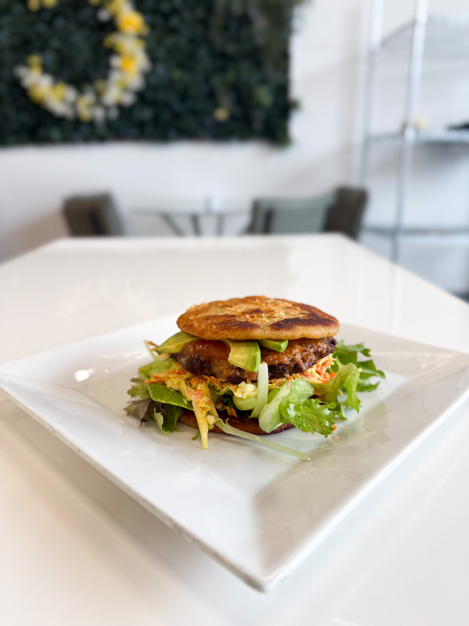 The Gordita Burger - La Luna Cafe -  Meet the Gordita Burger, a twist on a cherished classic, crafted with gourmet flair. We trade the ordinary bun for warm, handmade corn tortillas—soft, and irresistibly authentic. Nestled inside is a perfectly seasoned all-beef patty with melty cheese. A lively mix of spring greens and crisp repollo-cabbage salad, house red salsa, and fresh slices of avocado. Paired with a side of street corn—smoky, tangy, and irresistibly rich.