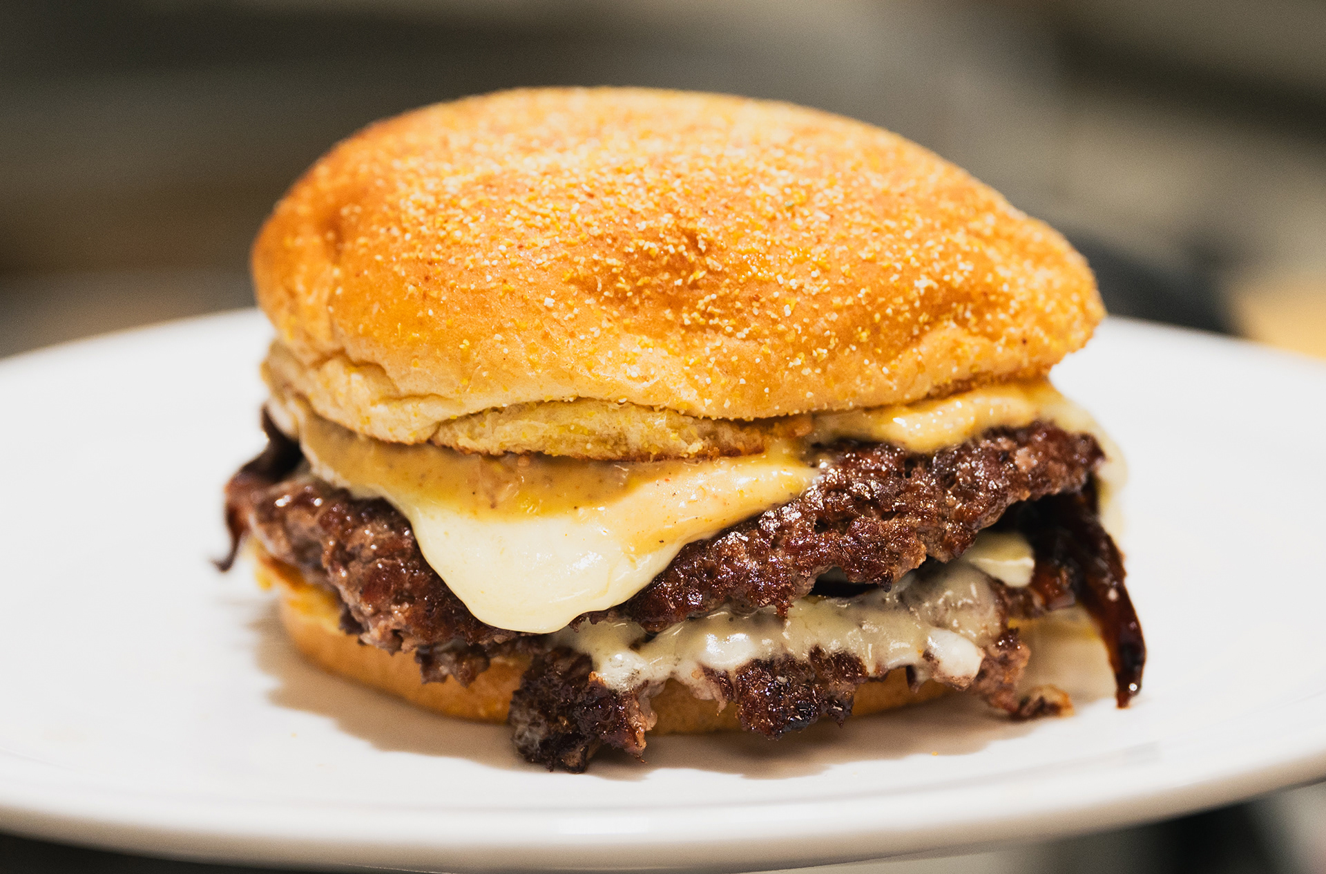 The Luchador Smash Burger - Pomegranate Market - Svec farm grass fed beef, chihuahua cheese, caramelized onions and Anaheim peppers with sweet corn chorizo aioli, cilantro lime mustard on a cornmeal dusted bun. 